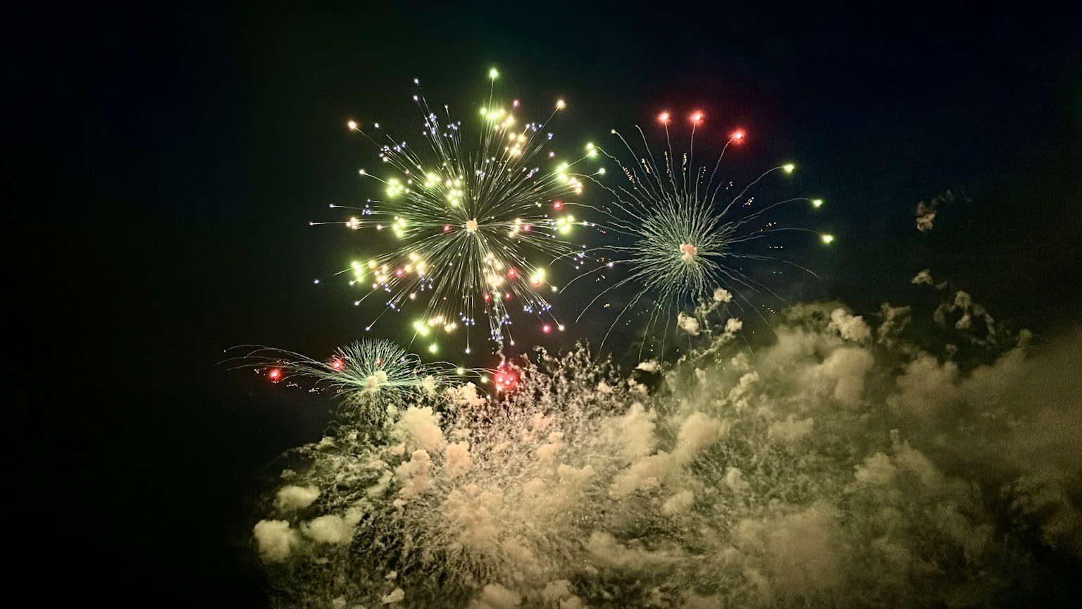 Colorful fireworks bursting in the night sky with clouds