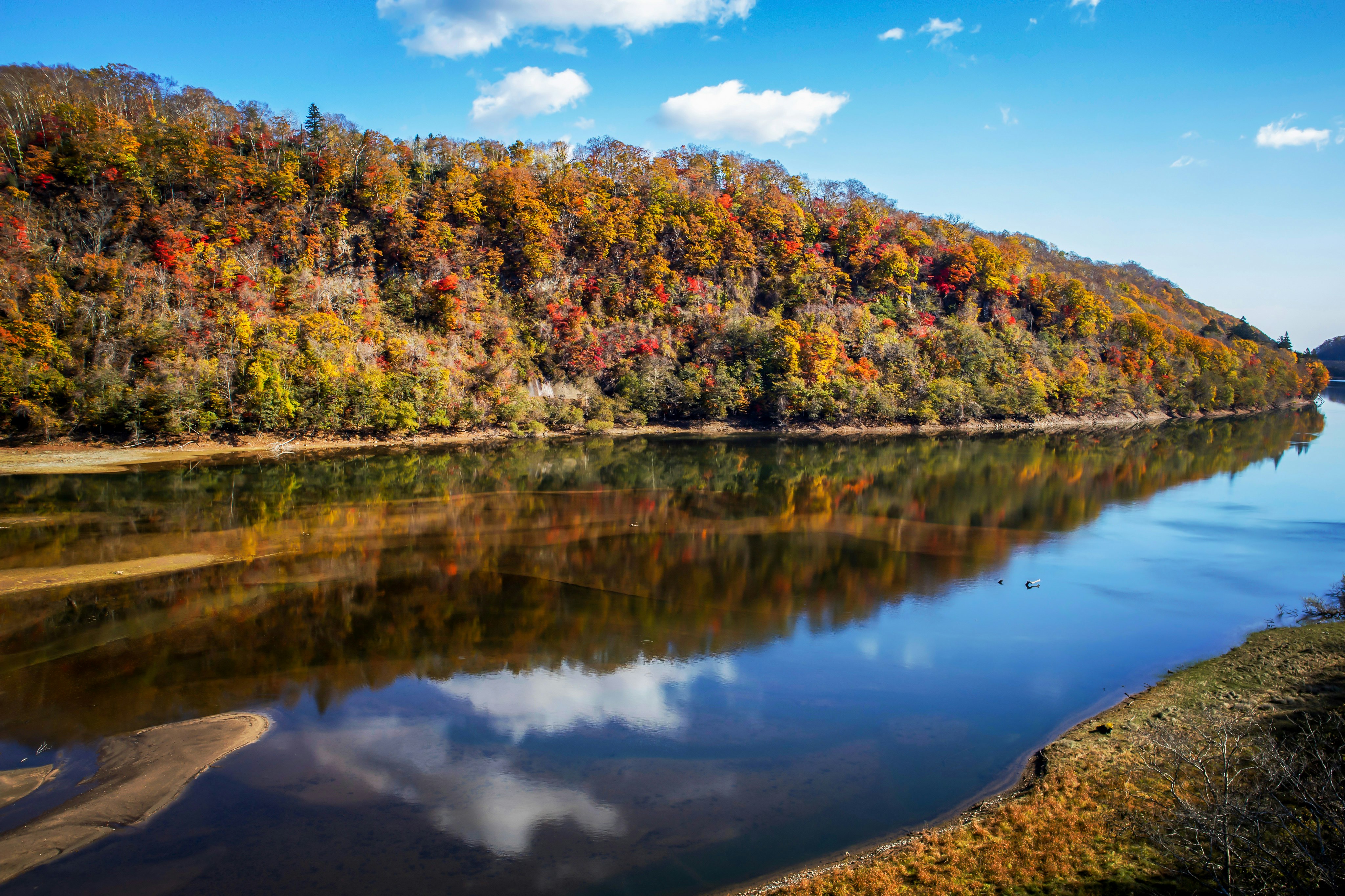 紅葉の山並みと湖面に映る静かな風景