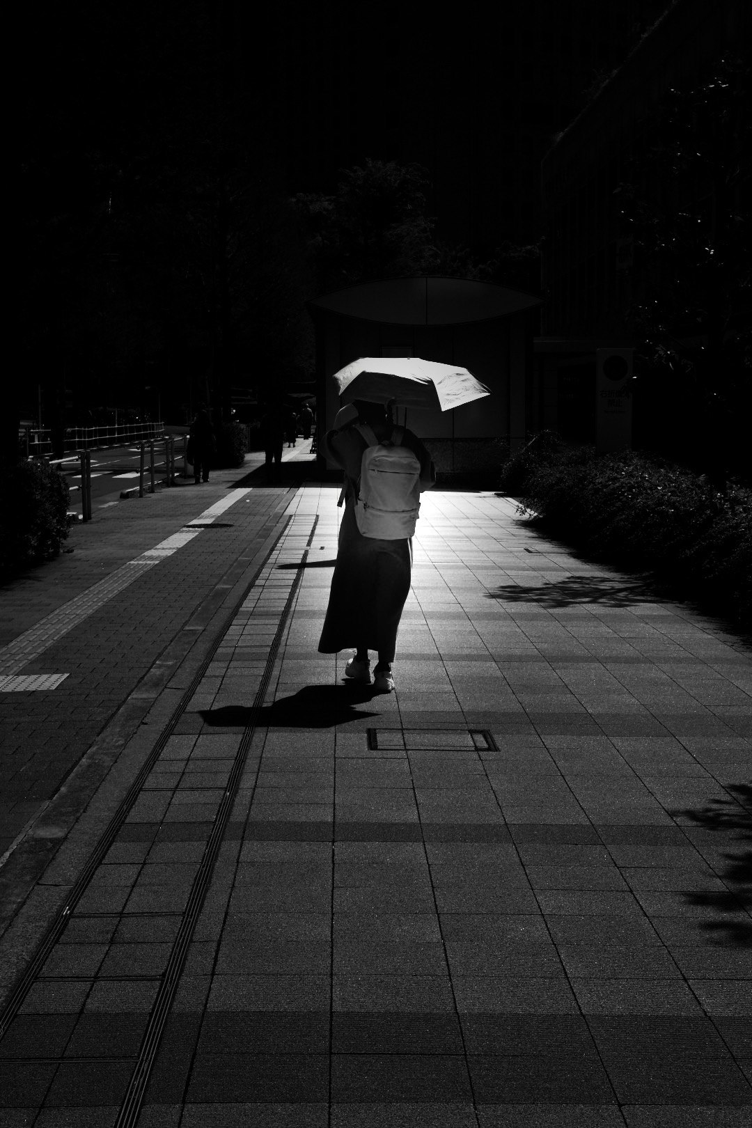 夜の屋外通路を歩く人物の後ろ姿