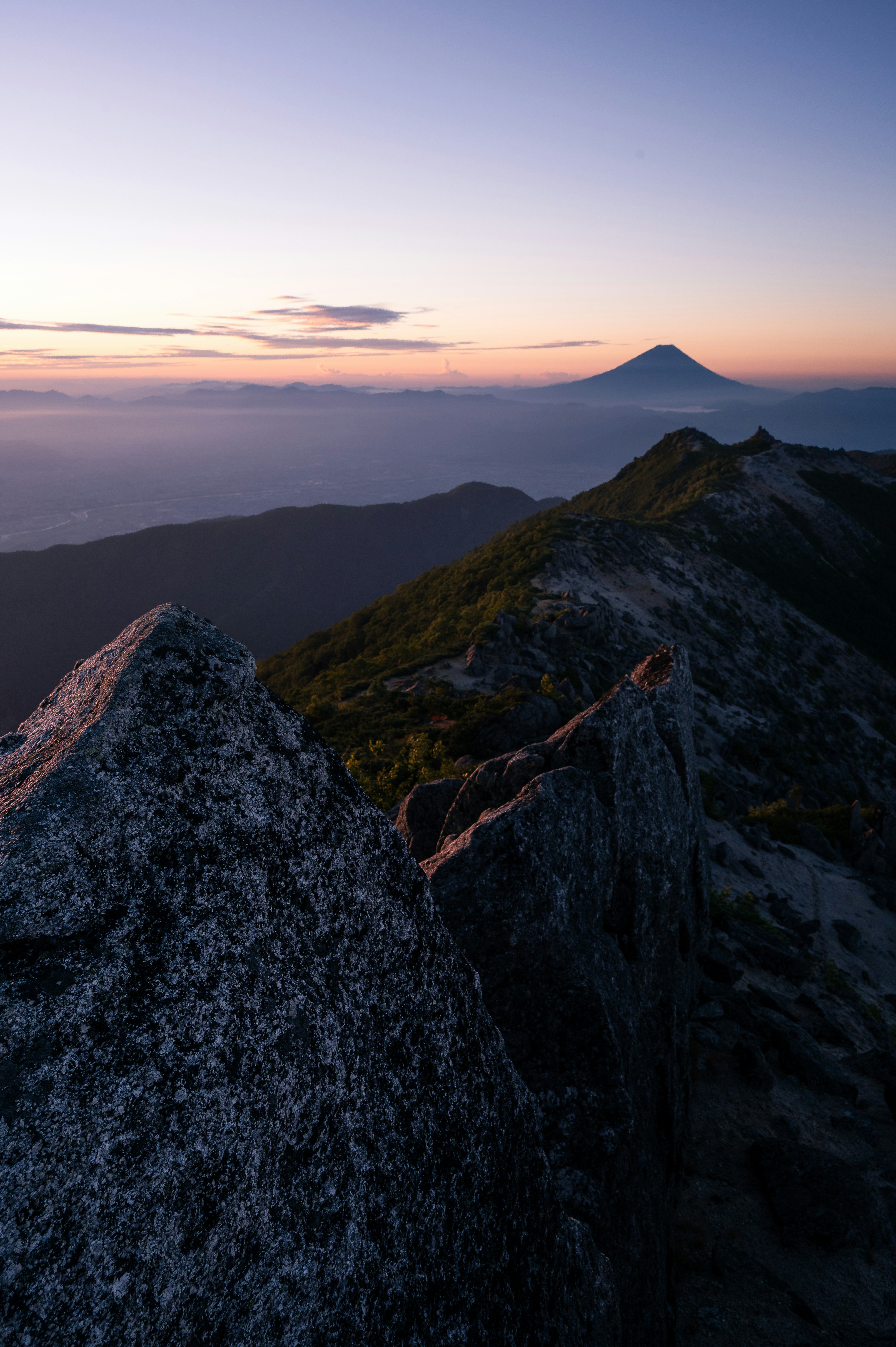 稜線から望む夕暮れの山並みと富士山のシルエット