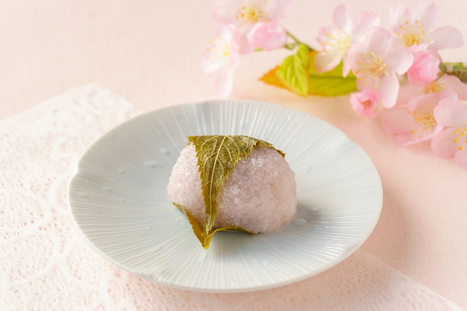 Bola de arroz envuelta en una hoja cerca de flores de cerezo