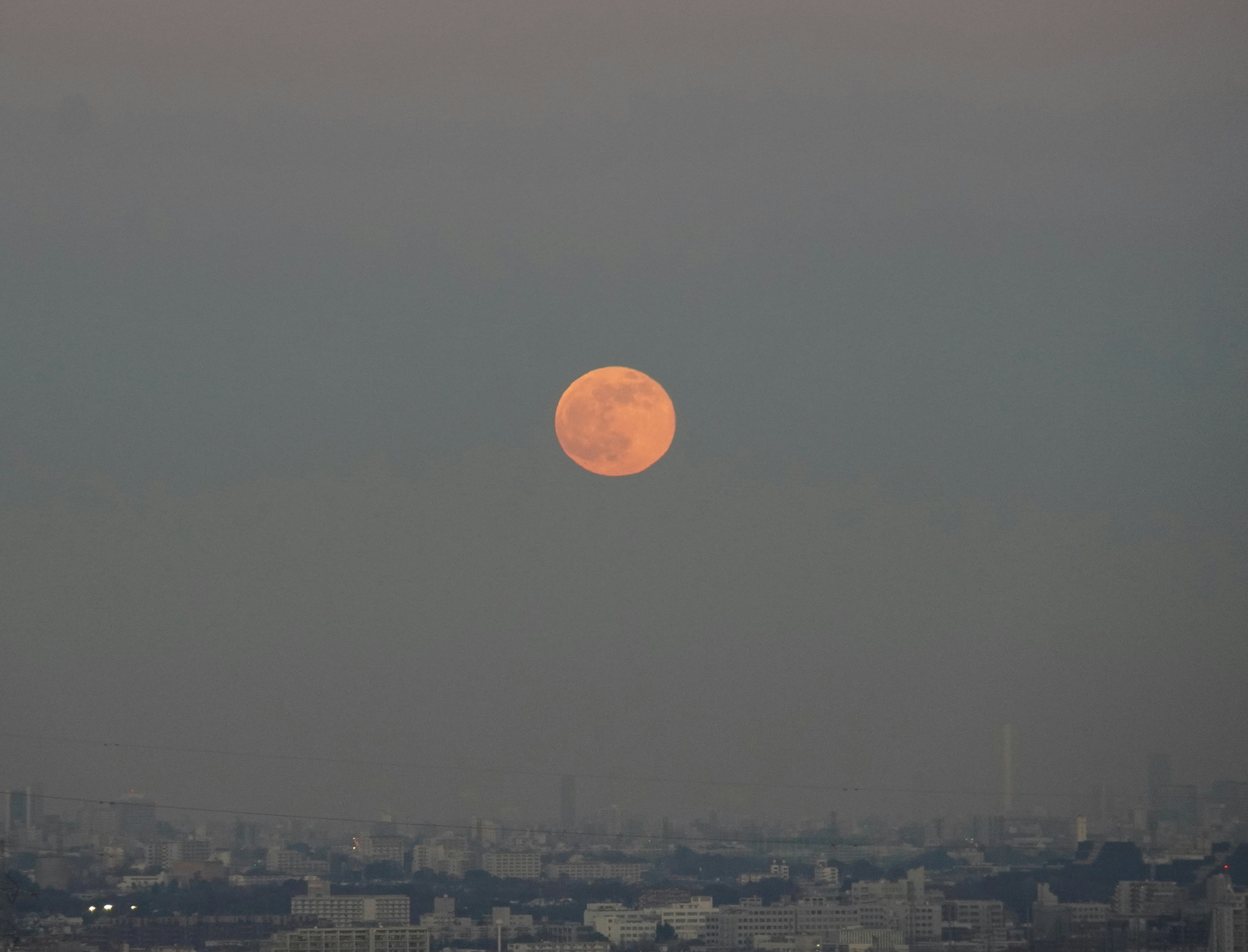 red full moon over a city skyline