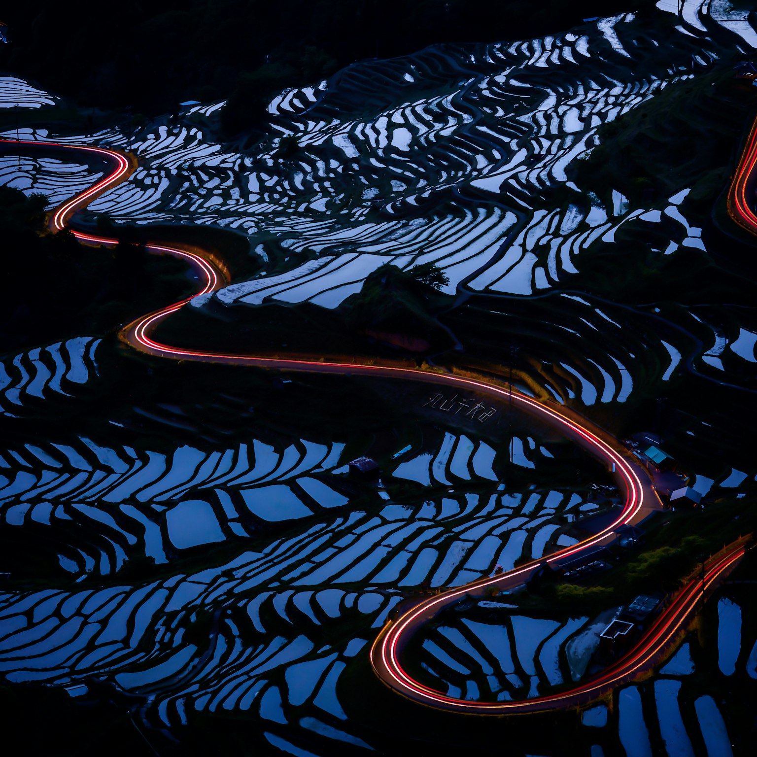 Beaux champs de riz en terrasses la nuit avec des lumières de route sinueuses