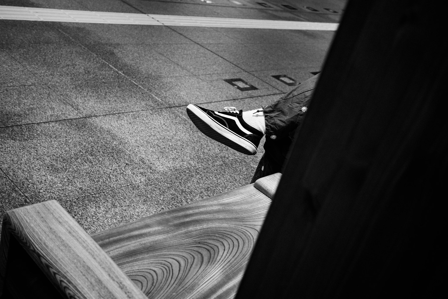 Chaussures noires et blanches reposant sur le sol partie d'un banc visible