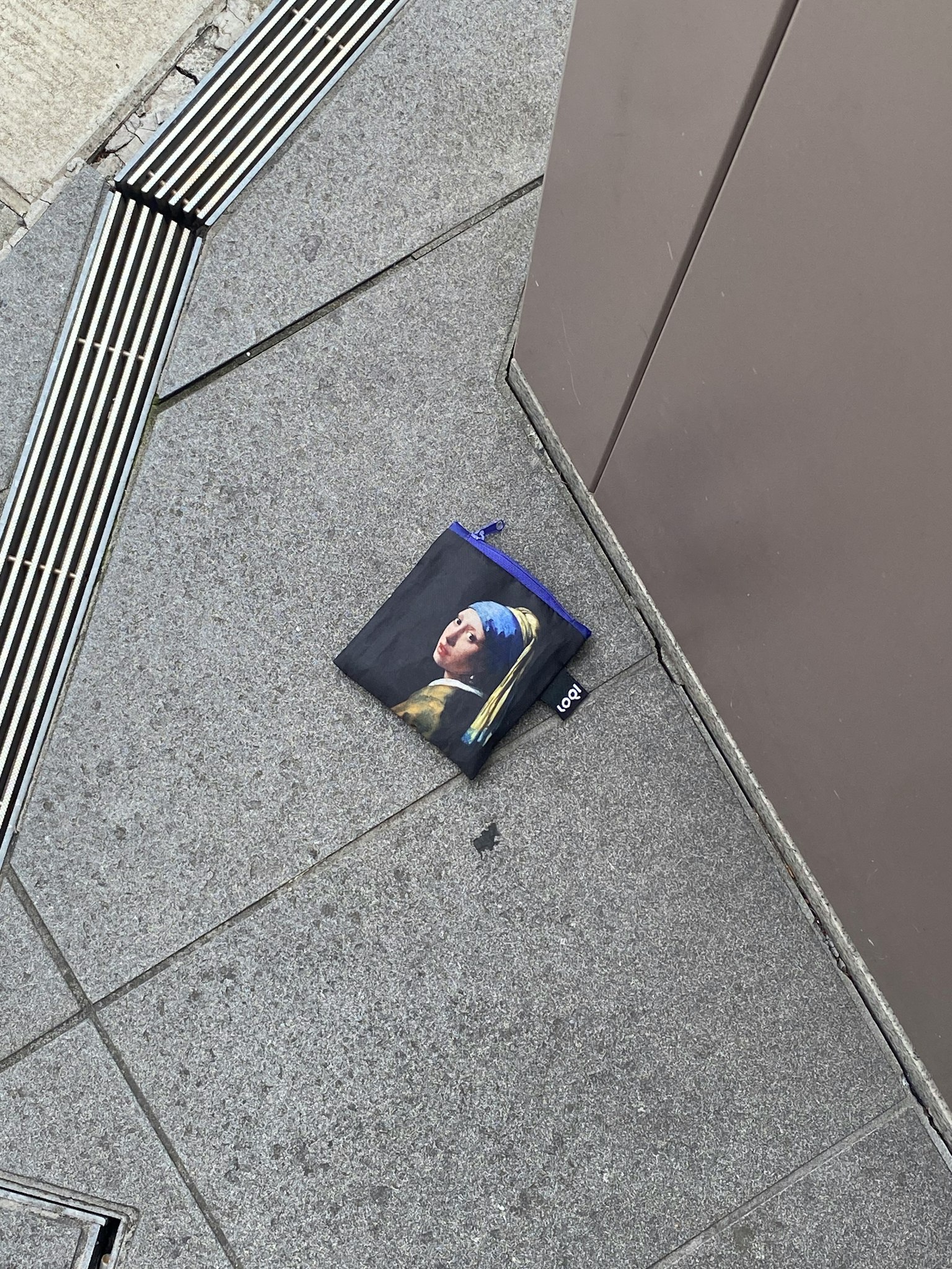 A blue pouch with an image of a girl lying on the ground