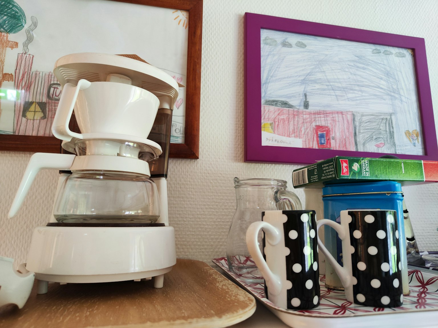 เครื่องชงกาแฟสีขาวกับถ้วยลายจุดสีดำในมุมครัวที่อบอุ่น