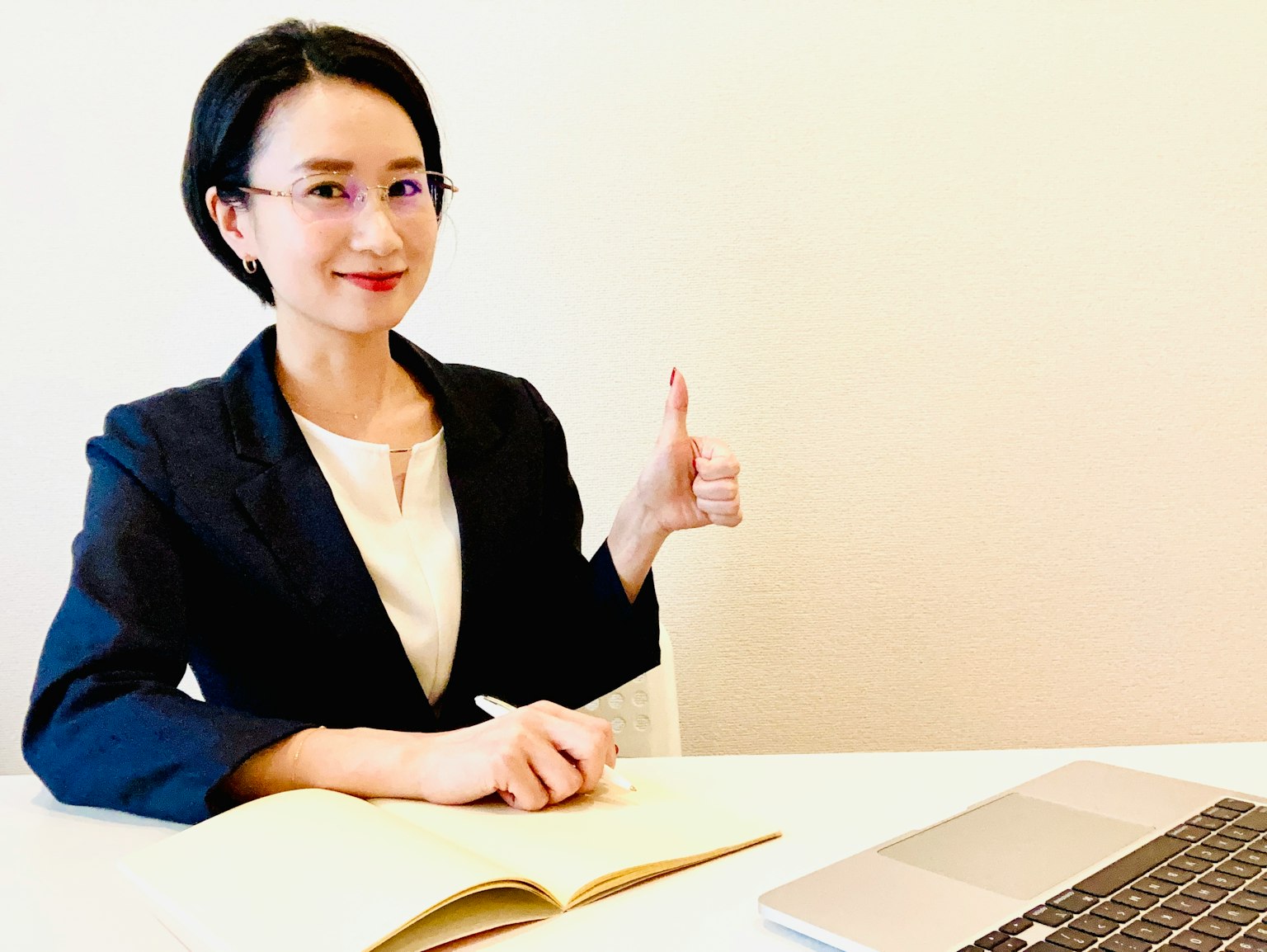 Une femme en costume d'affaires souriante et faisant un pouce levé