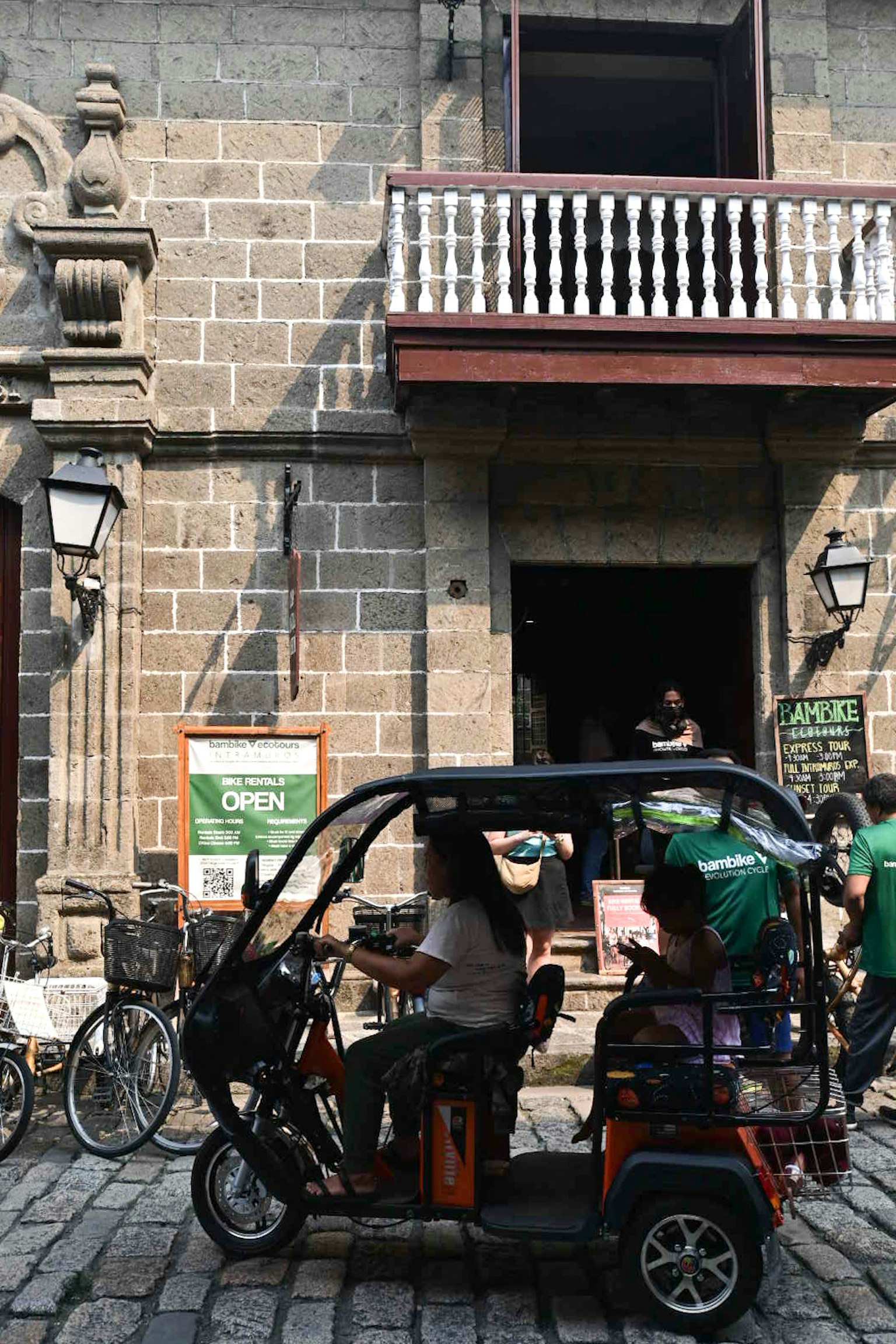 Triciclo che passa davanti a un edificio storico in pietra con un balcone