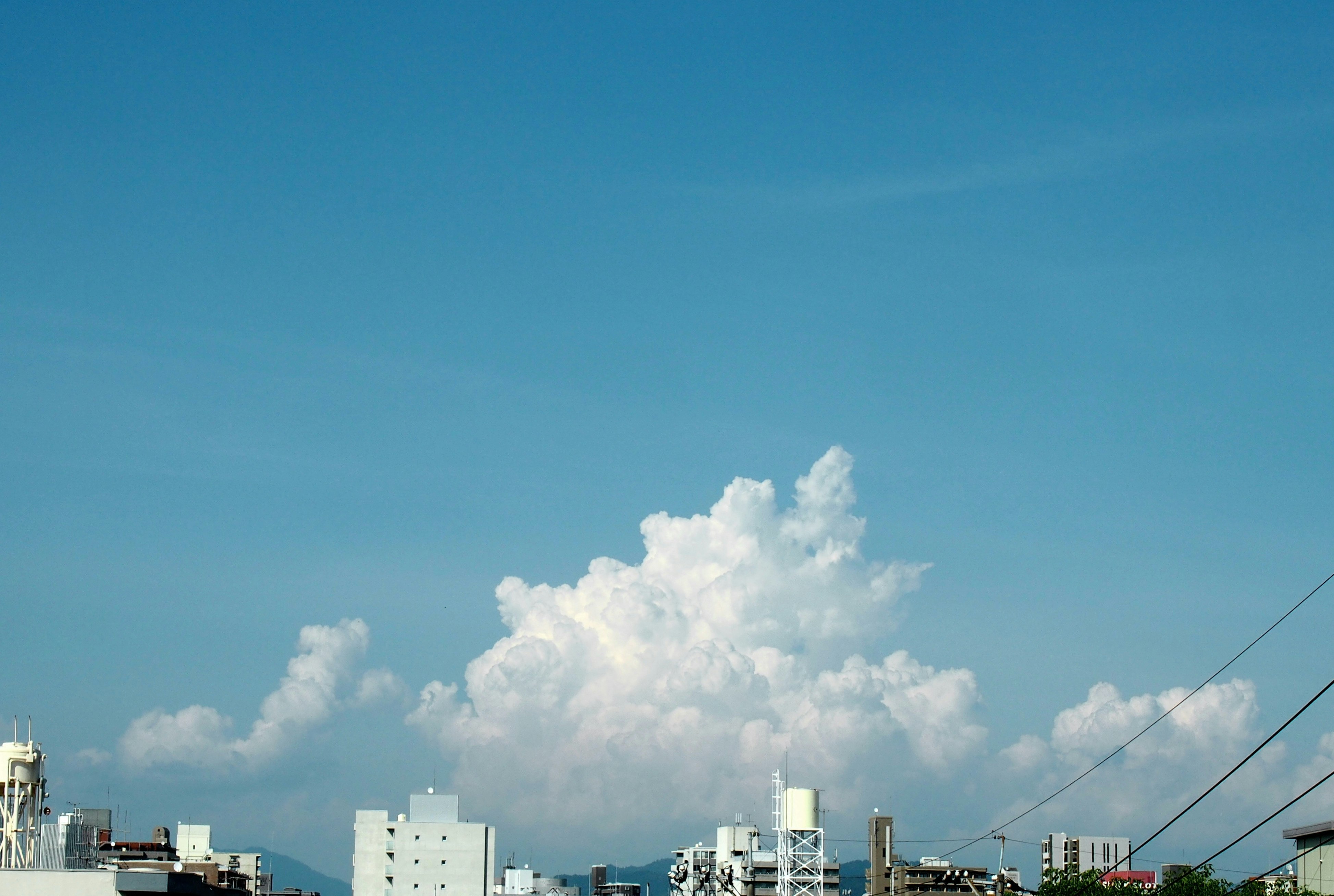 青空に浮かぶ大きな積雲と都市の建物群
