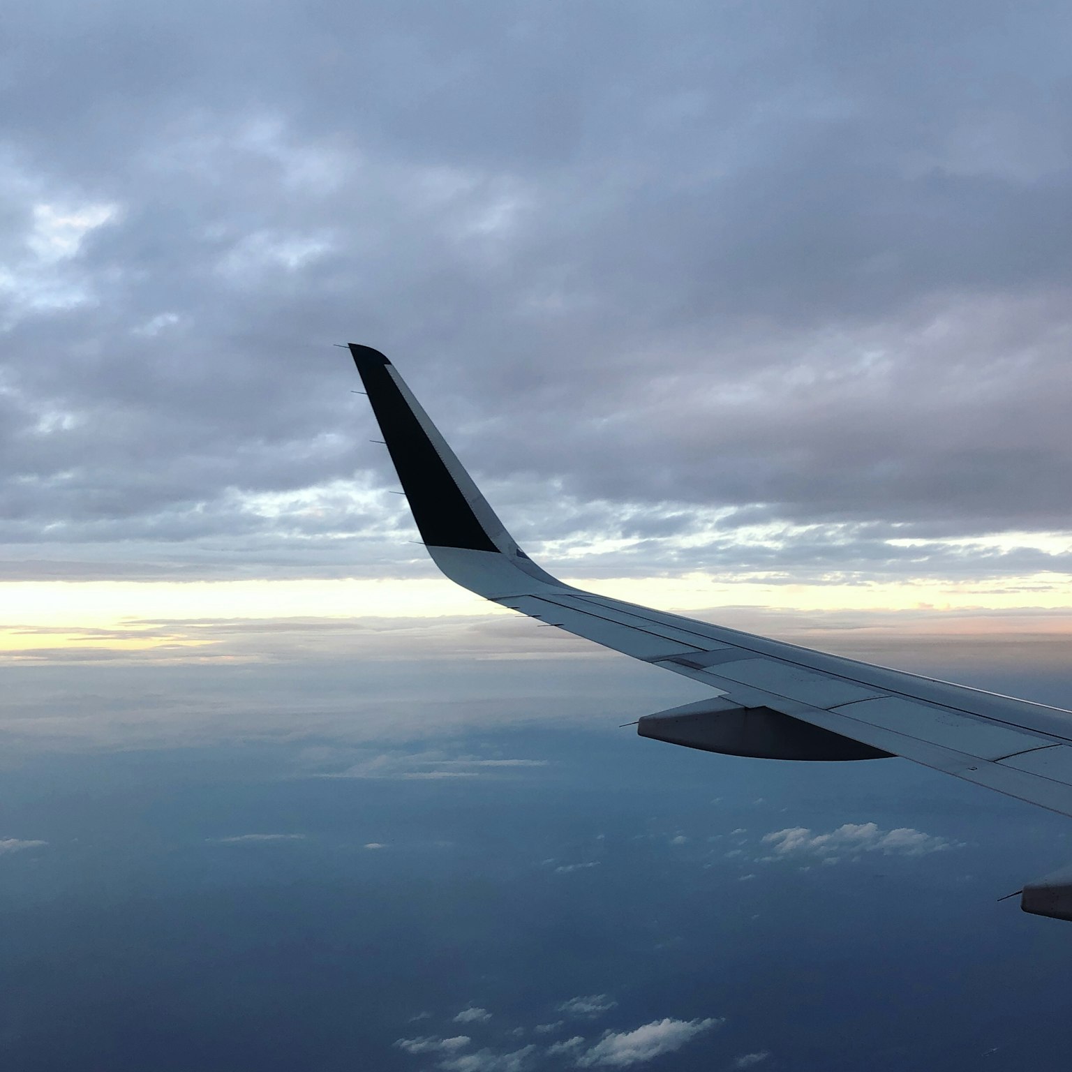 飛機翼與夕陽下的多雲天空