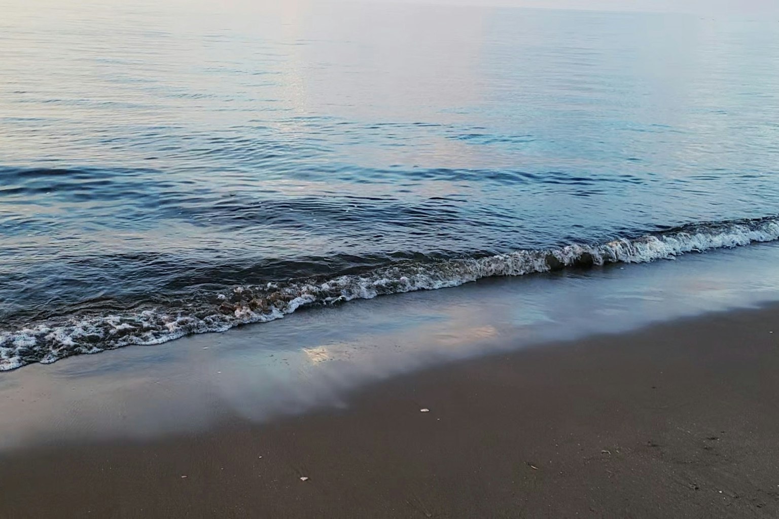 平靜的海洋和沙灘場景日落的倒影在水面上