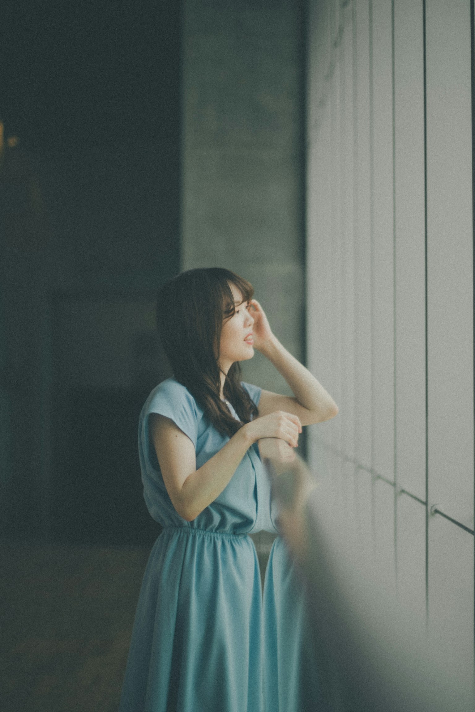 Woman in a blue dress looking out the window