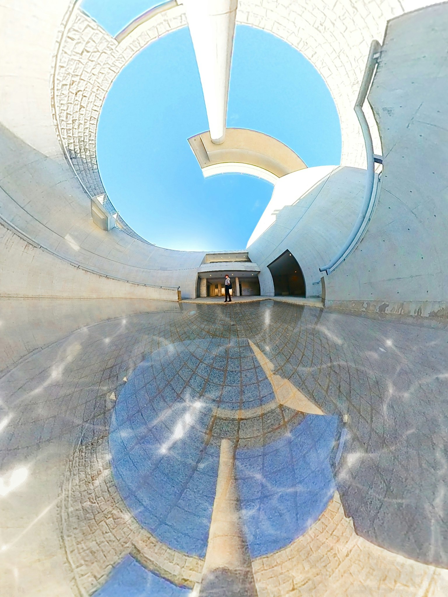 Design architettonico circolare con riflessi di luce e cielo blu