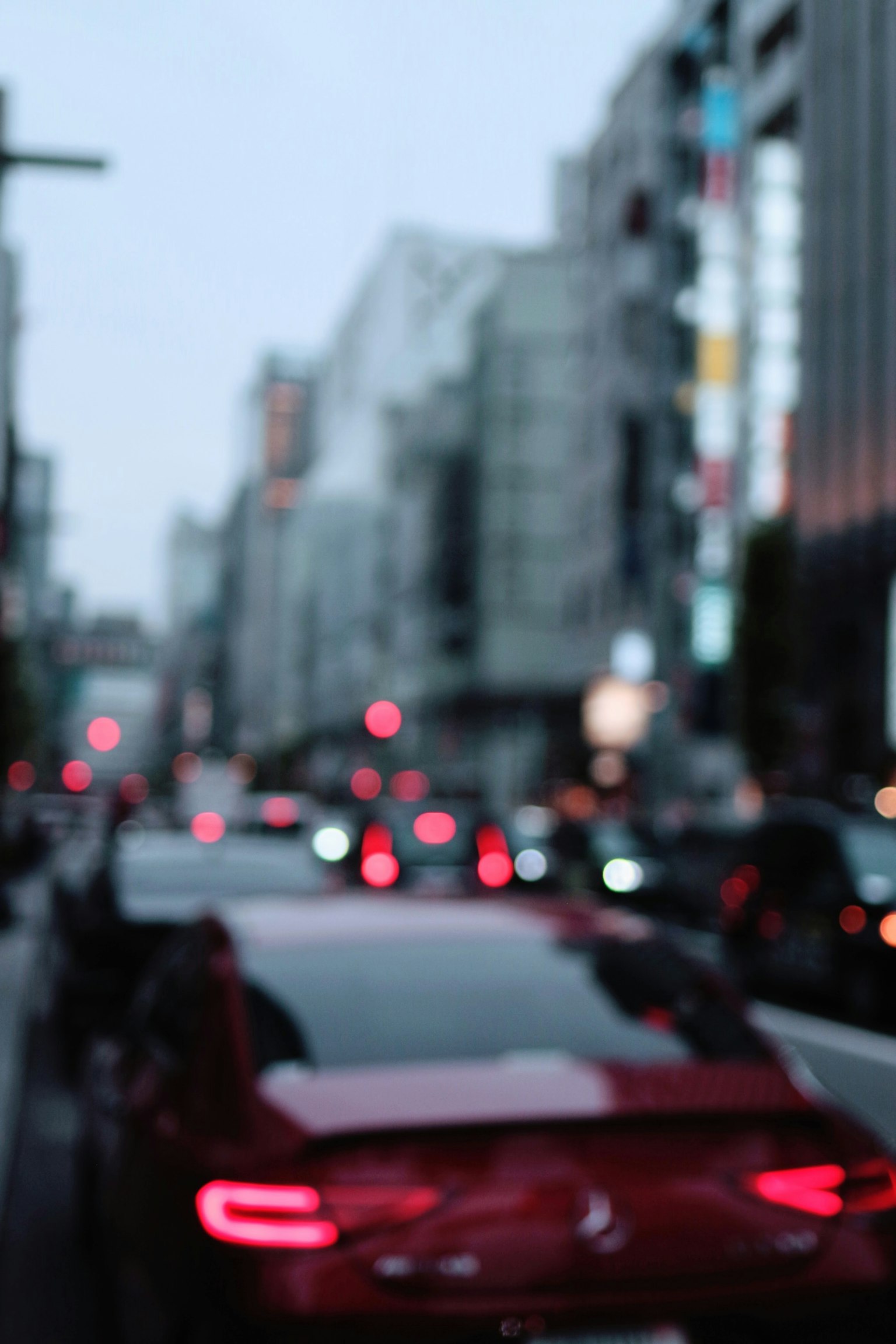 Paesaggio urbano sfocato con un'auto rossa e lampioni luminosi