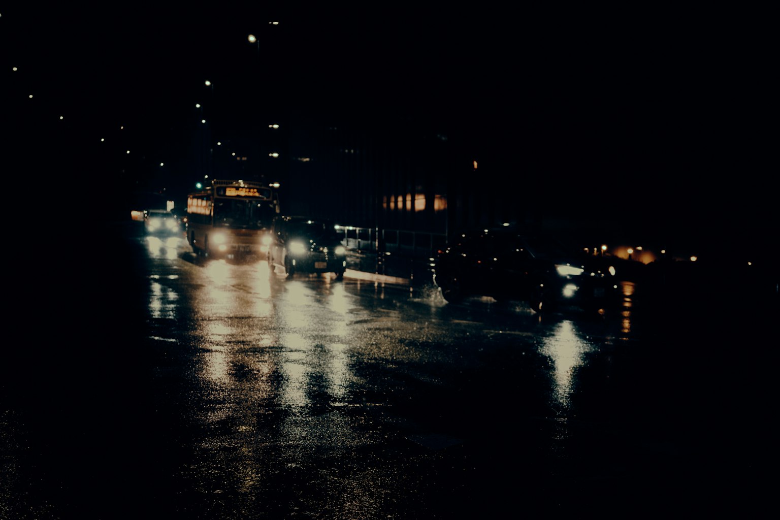 City street at night with reflections in puddles and car lights