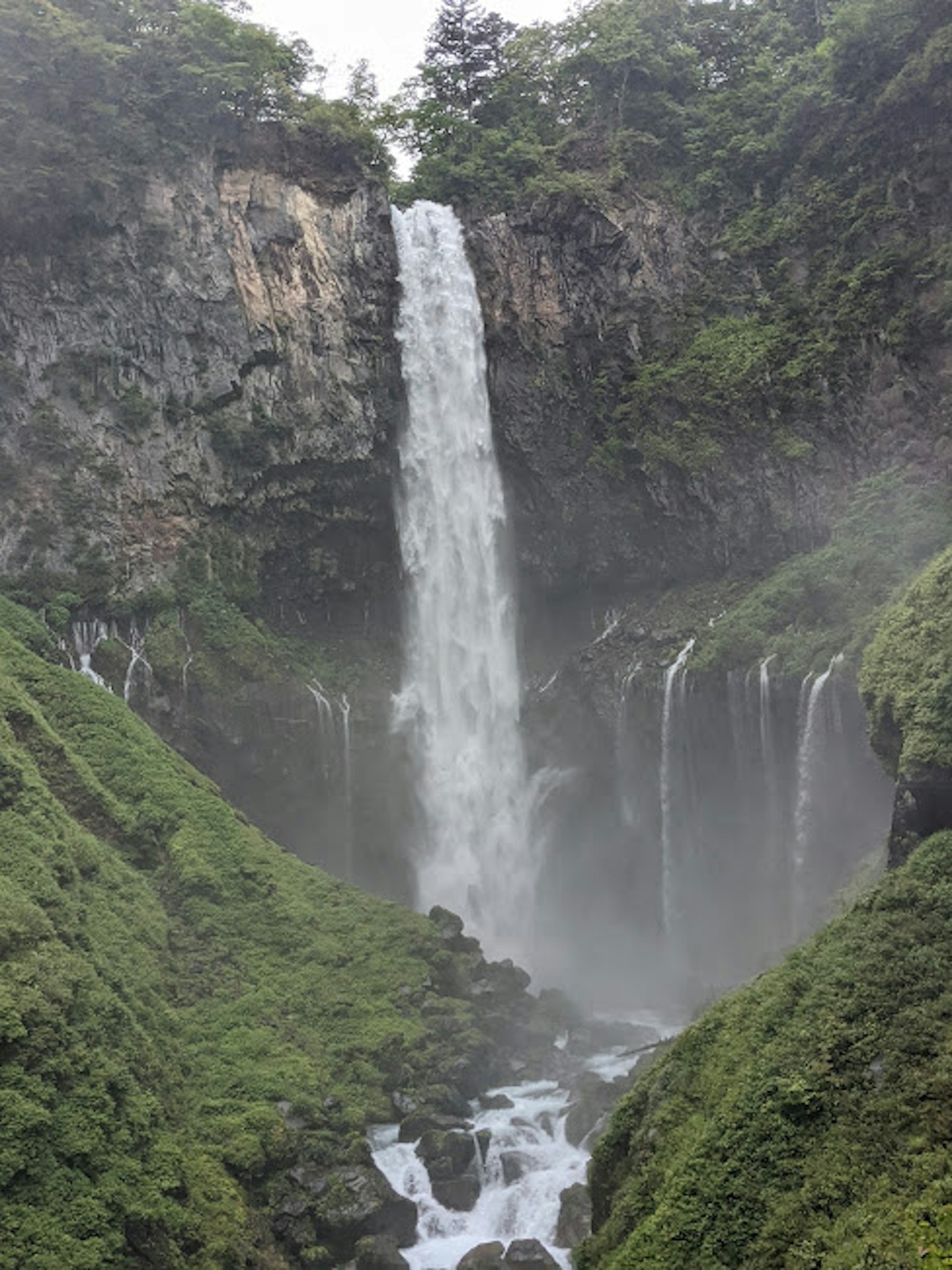 Majestic waterfall surrounded by lush green mountains and mist