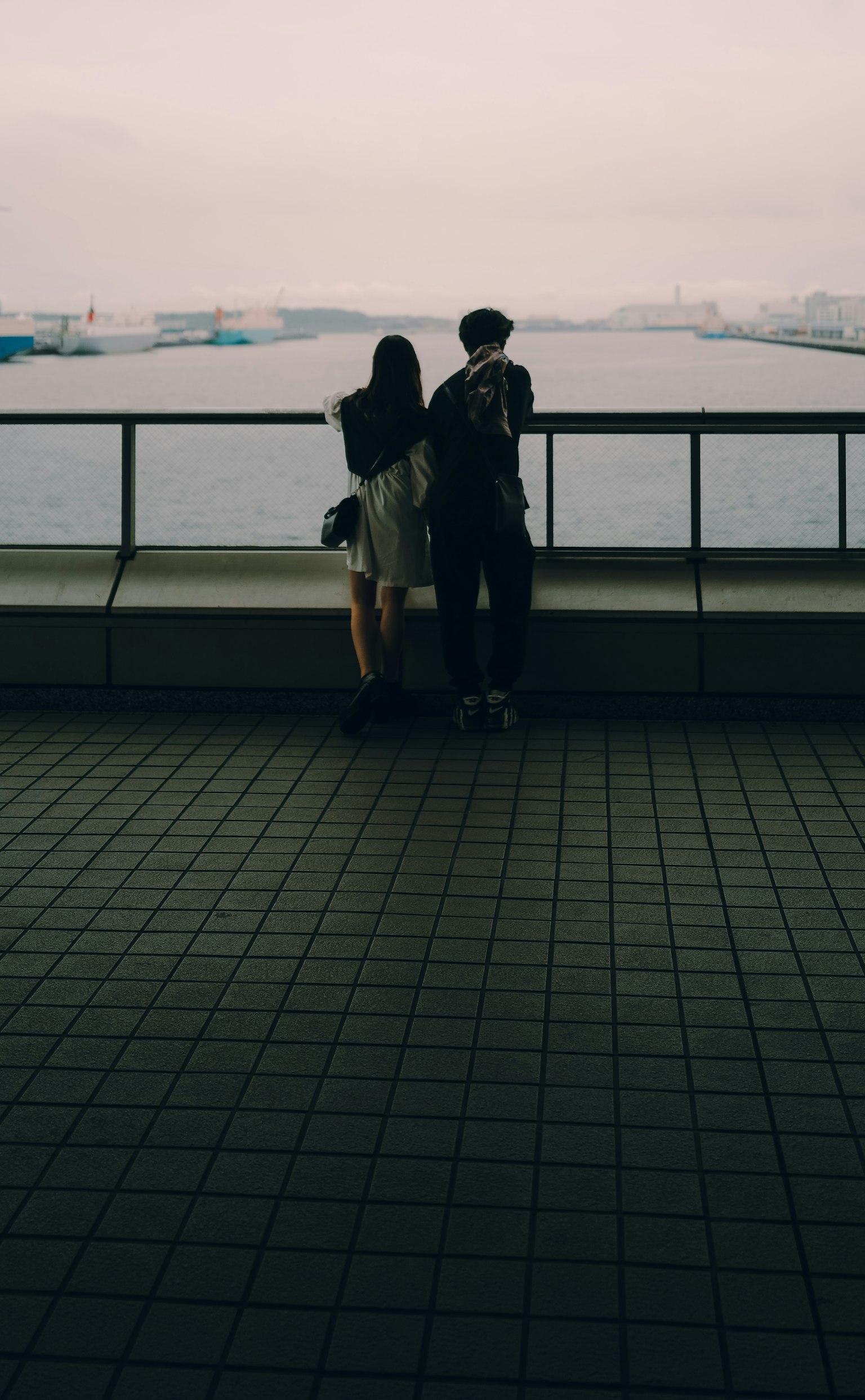 Pareja mirando el mar con un cielo nublado y agua al fondo