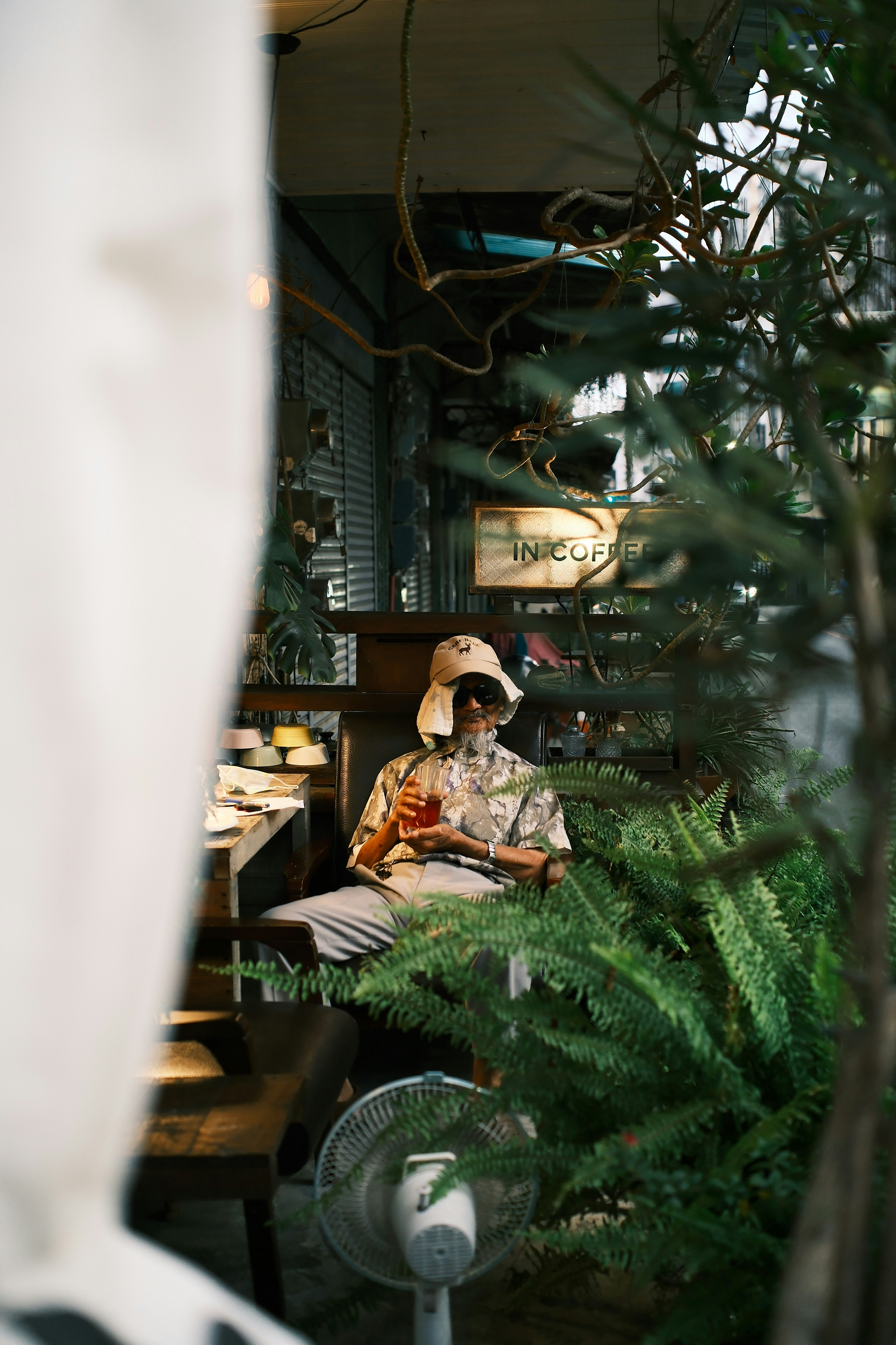 緑の植物に囲まれたカフェでリラックスする人
