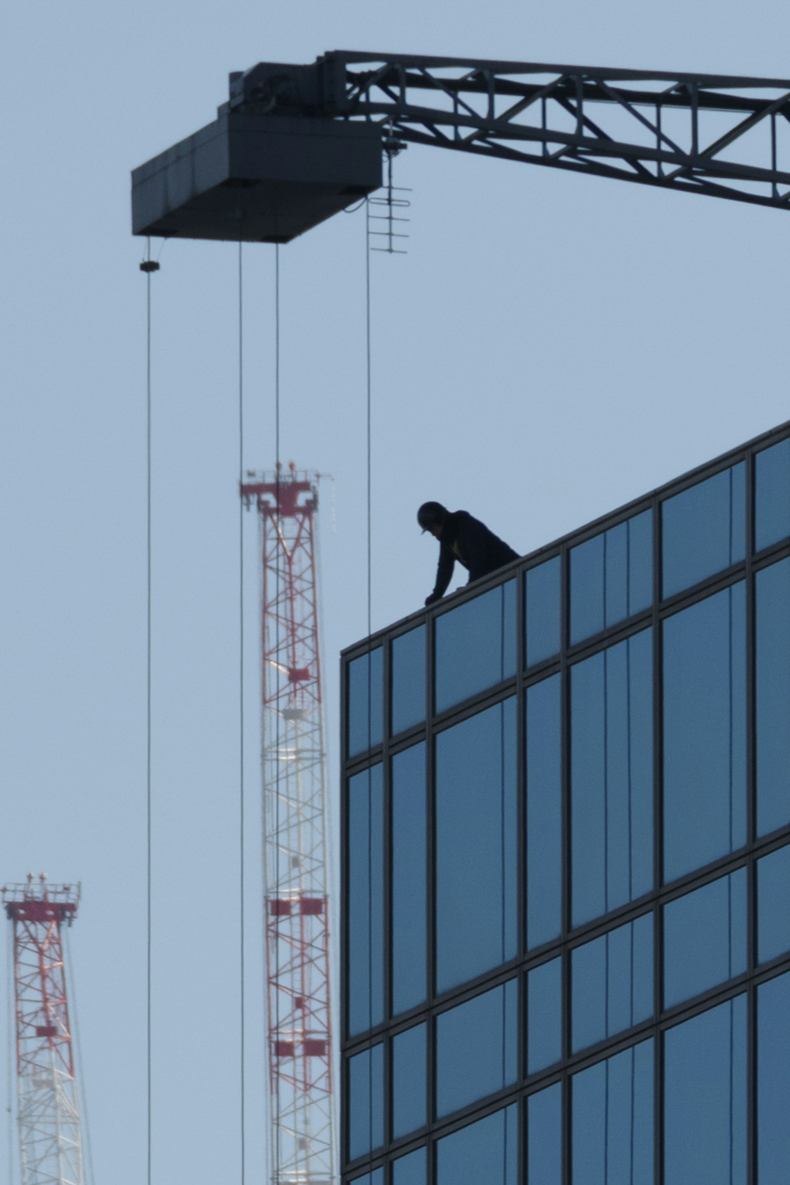 高層建築屋頂上工作的建築工人輪廓