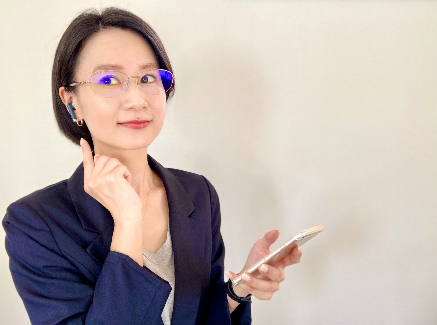 一位女性手持智能手机，表情沉思，佩戴蓝光眼镜