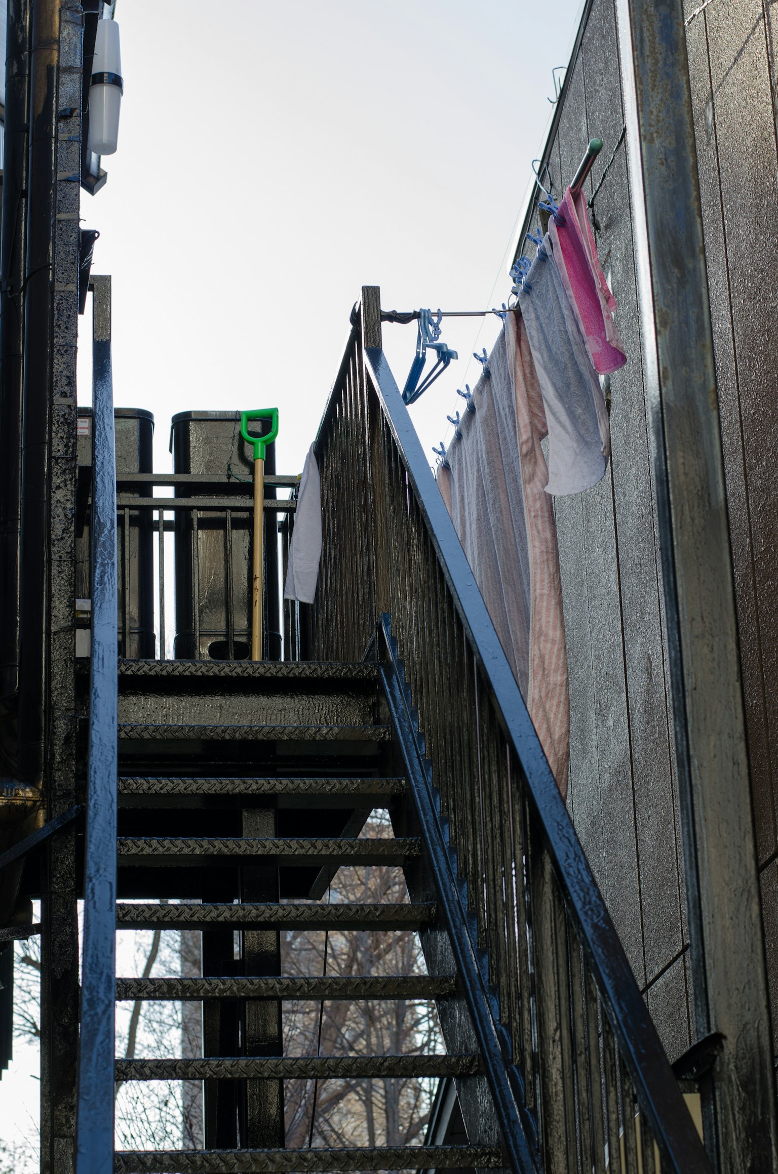 Vue extérieure d'un appartement avec un escalier et du linge suspendu au-dessus