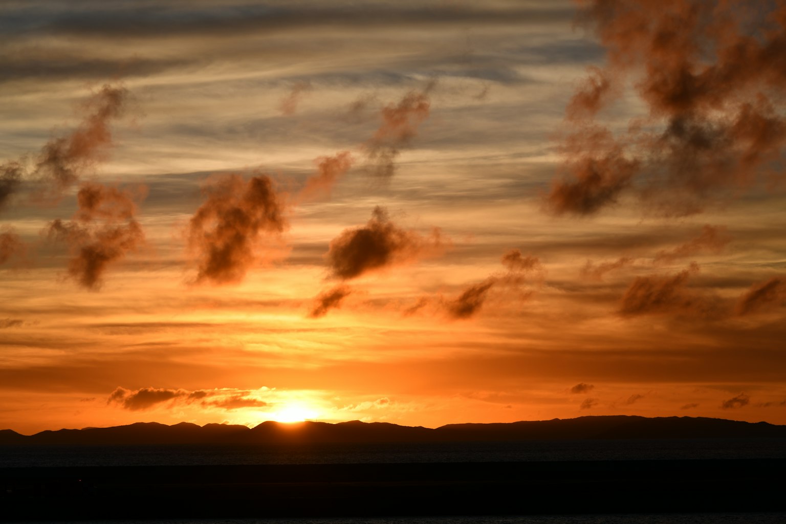 Schöne Sonnenuntergangslandschaft mit orange und gelbem Himmel und fernen Bergen