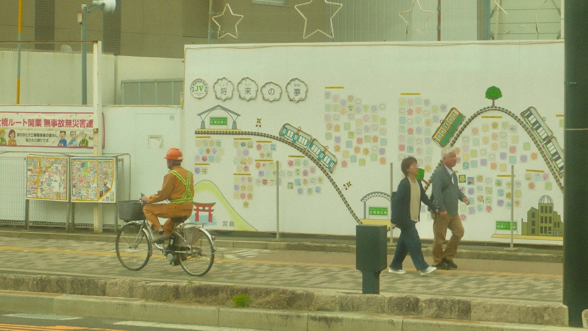 壁面のイラストがある屋外の展示スペース前で自転車と人