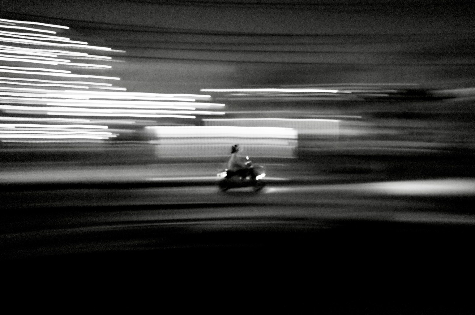 Photographie en flou de mouvement montrant un motard traversant un arrière-plan flou