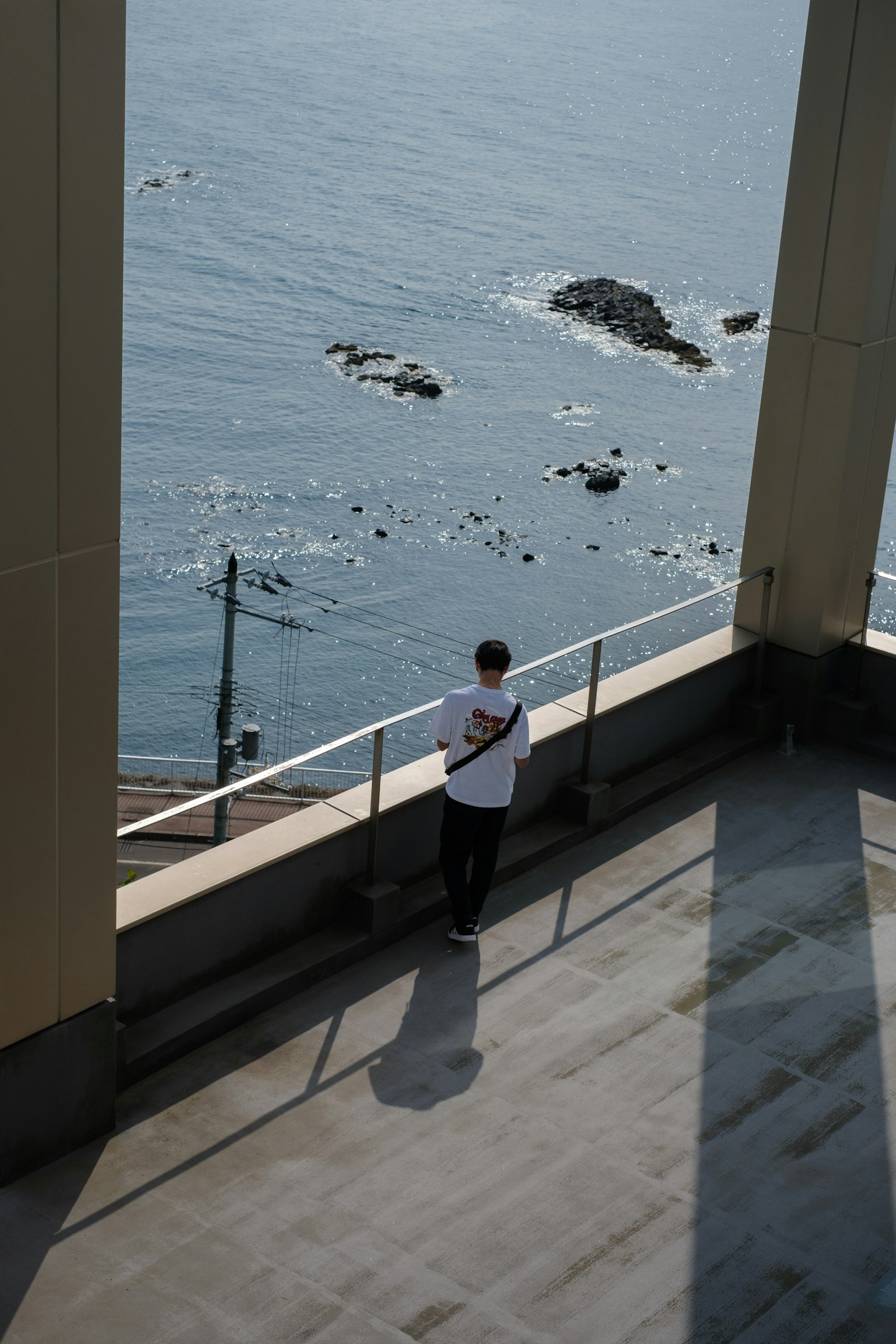 Un homme debout regardant la mer avec des rochers visibles à proximité