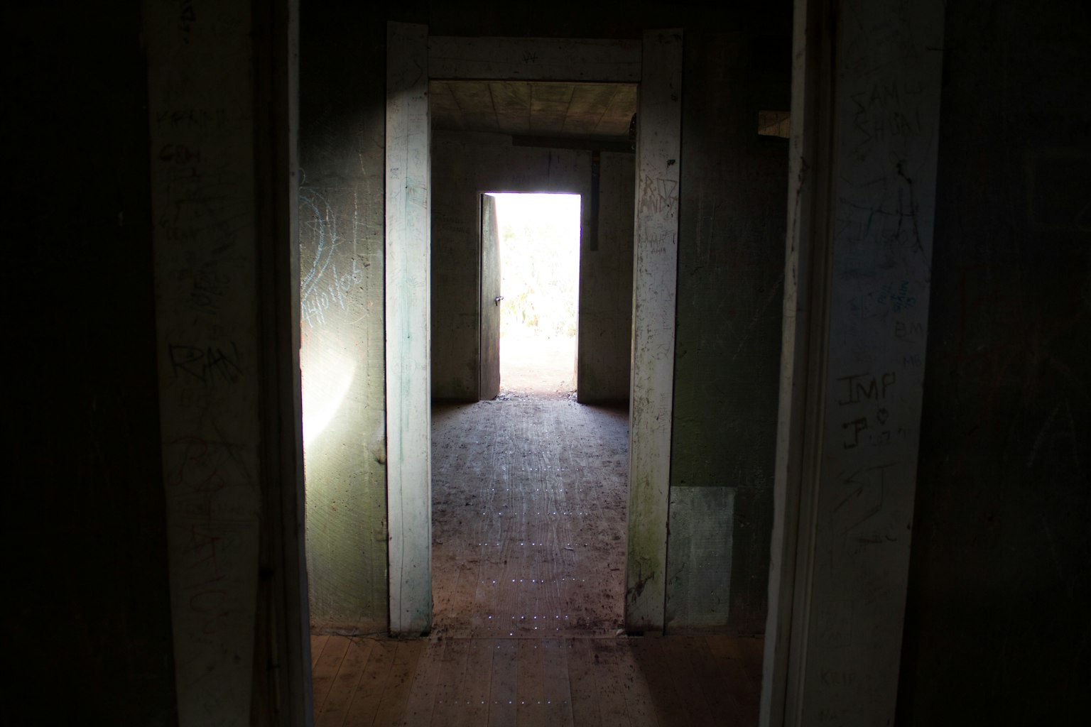 Interno di un vecchio edificio con un corridoio buio che porta a una luce brillante