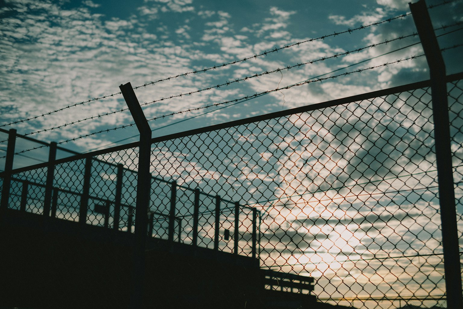 Silhouette de una cerca contra un cielo al atardecer