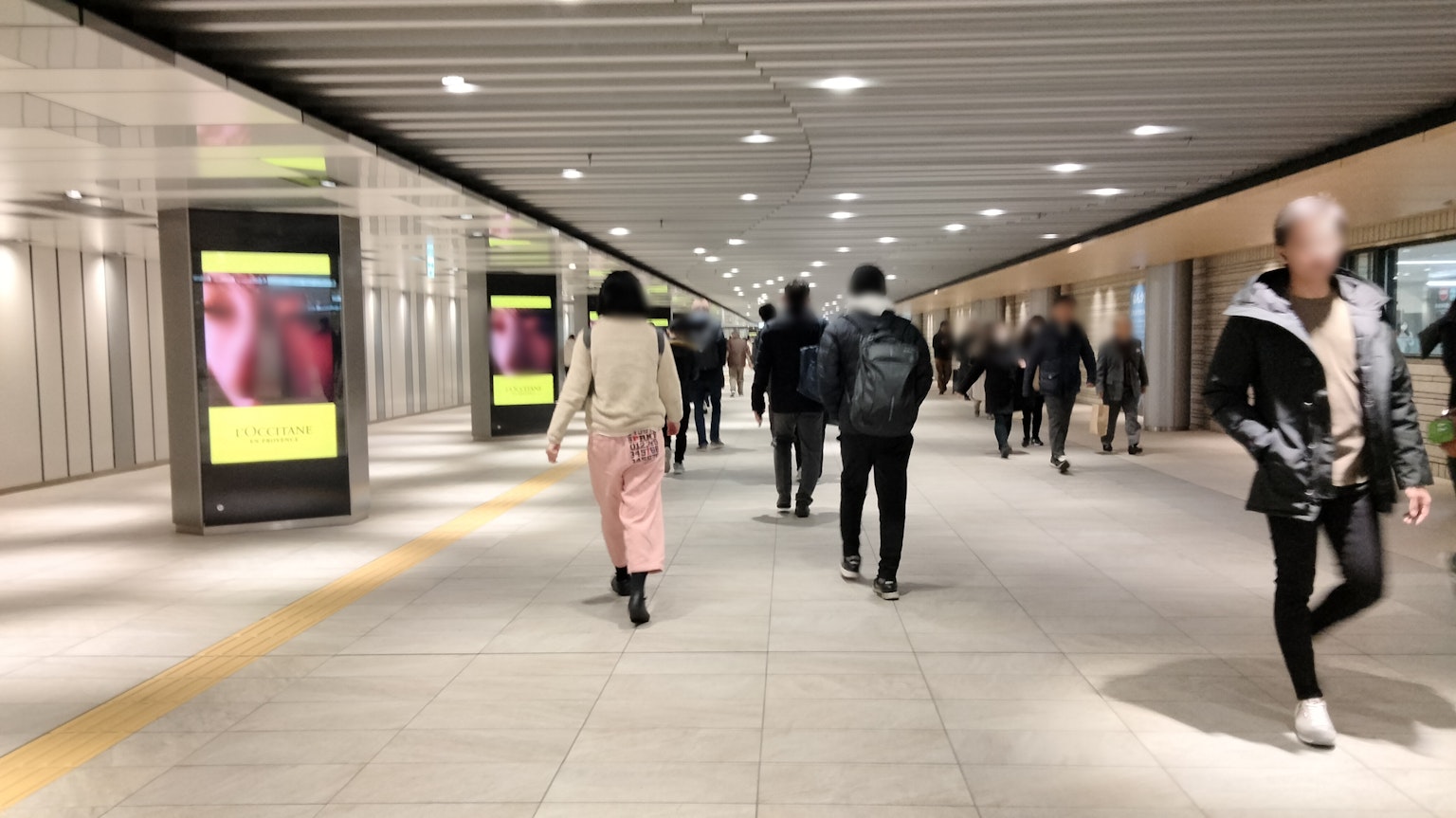 Un passage souterrain lumineux avec des gens marchant et des publicités