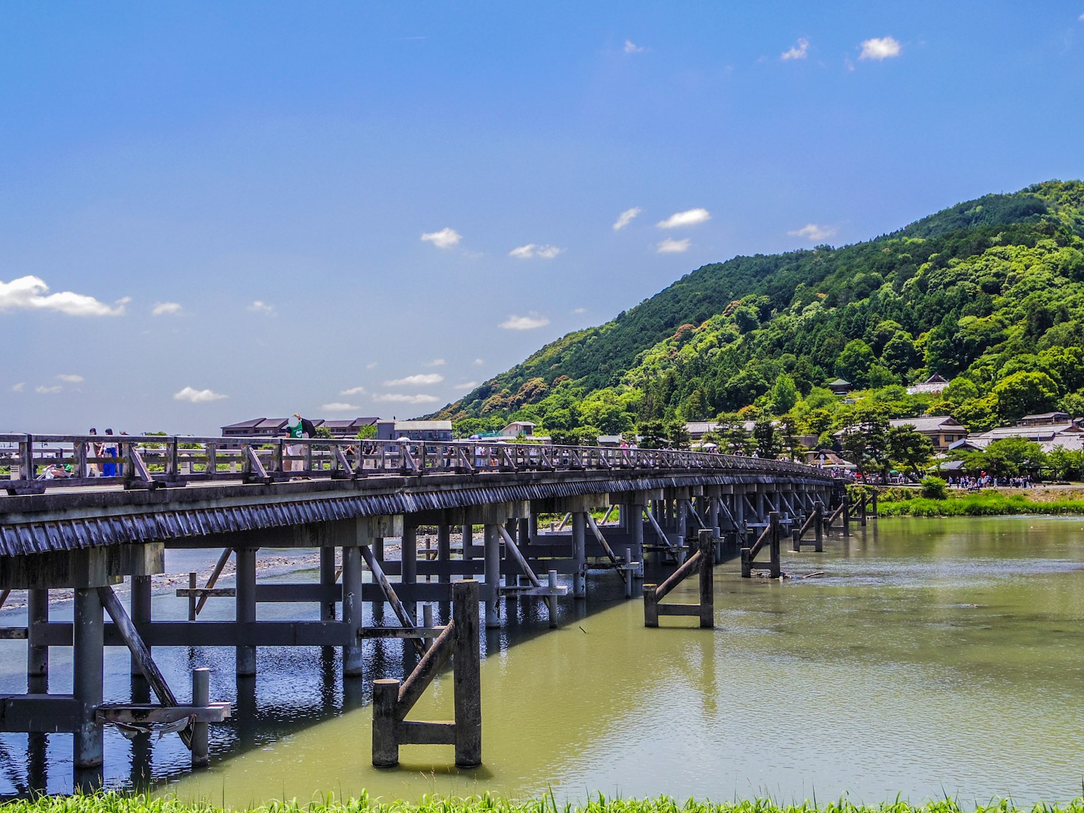 สะพานสวยใต้ท้องฟ้าสีฟ้ากับภูเขาสีเขียวด้านหลัง