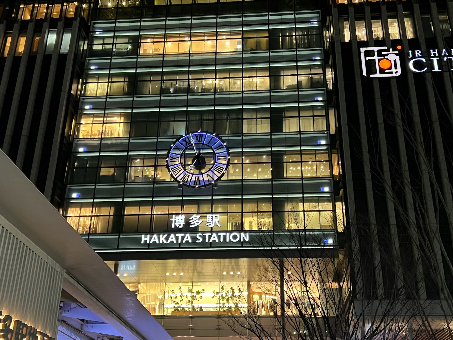 Vista notturna della stazione di Hakata con luci brillanti e architettura moderna con un design di orologio