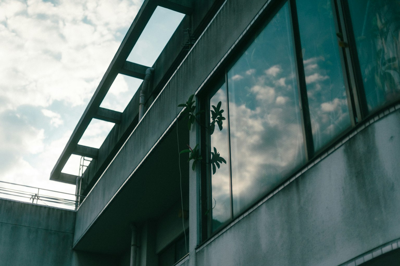 Modern building exterior with window reflections and cloudy sky