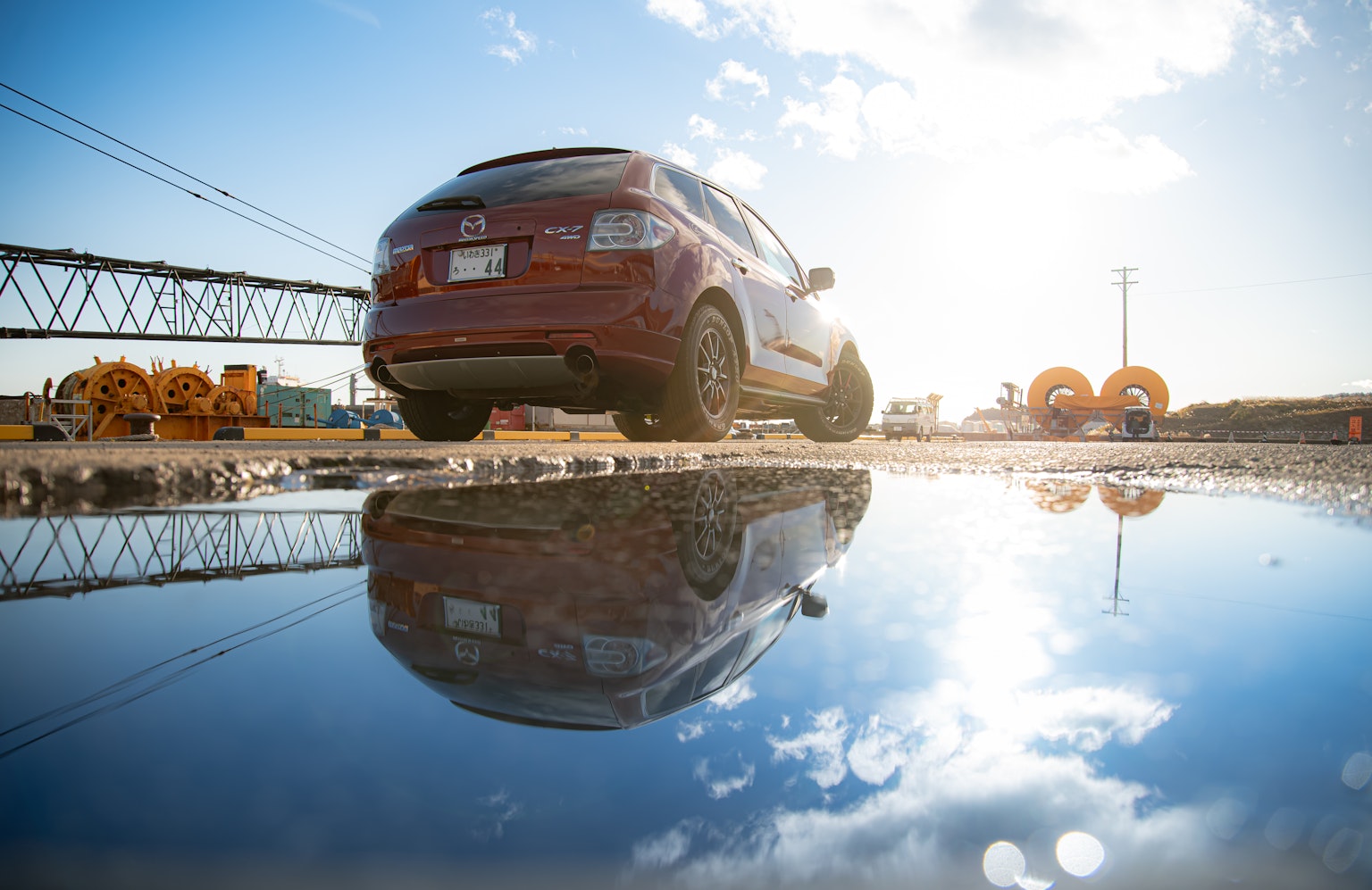 Voiture rouge réfléchie dans une flaque d'eau avec lumière du soleil