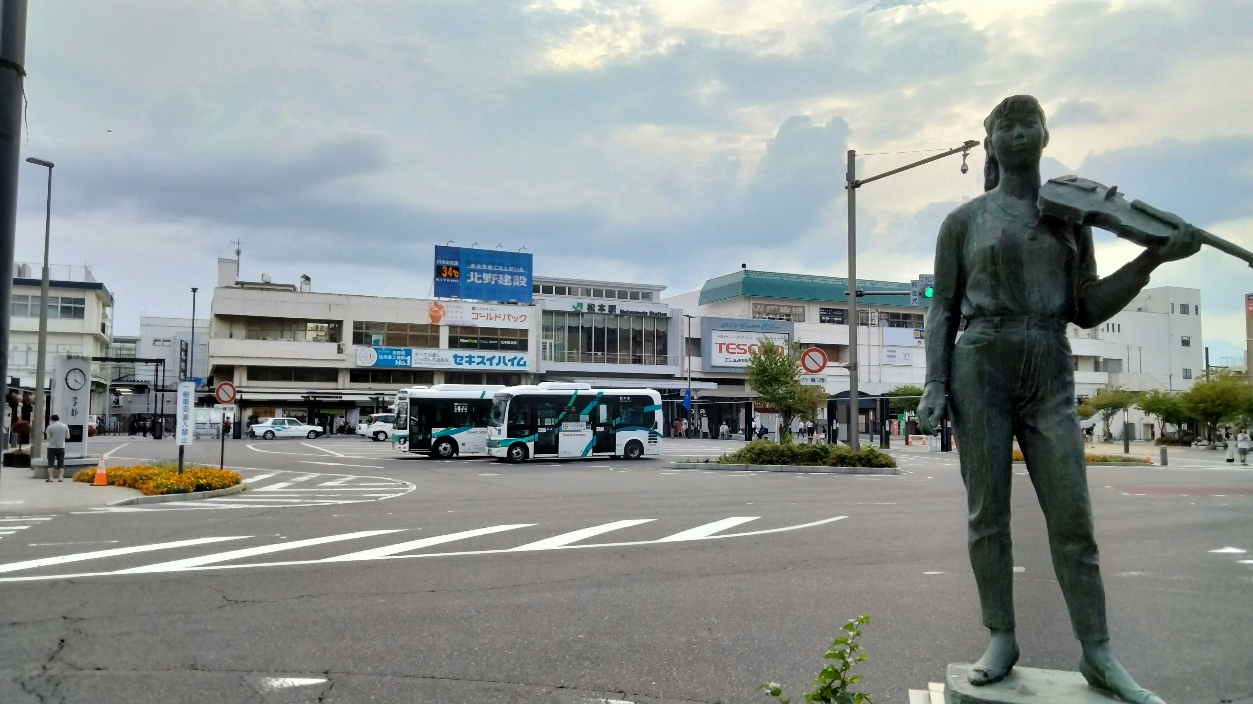 広い交差点と銅像のある駅前の街並み
