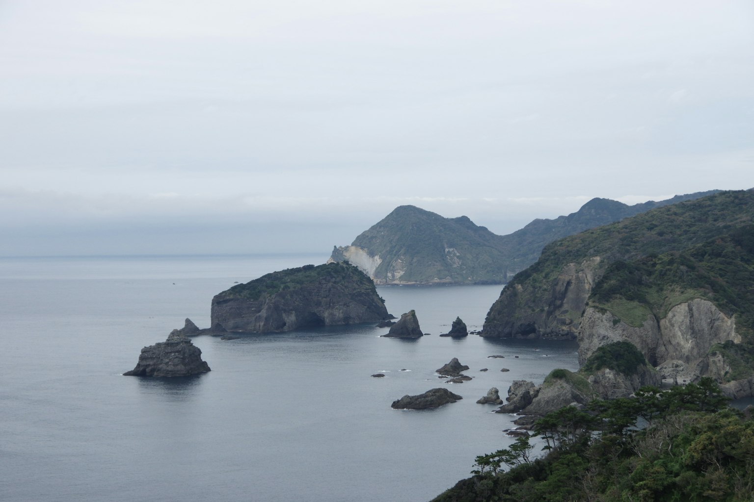 Pemandangan pantai dengan tebing berbatu dan gunung