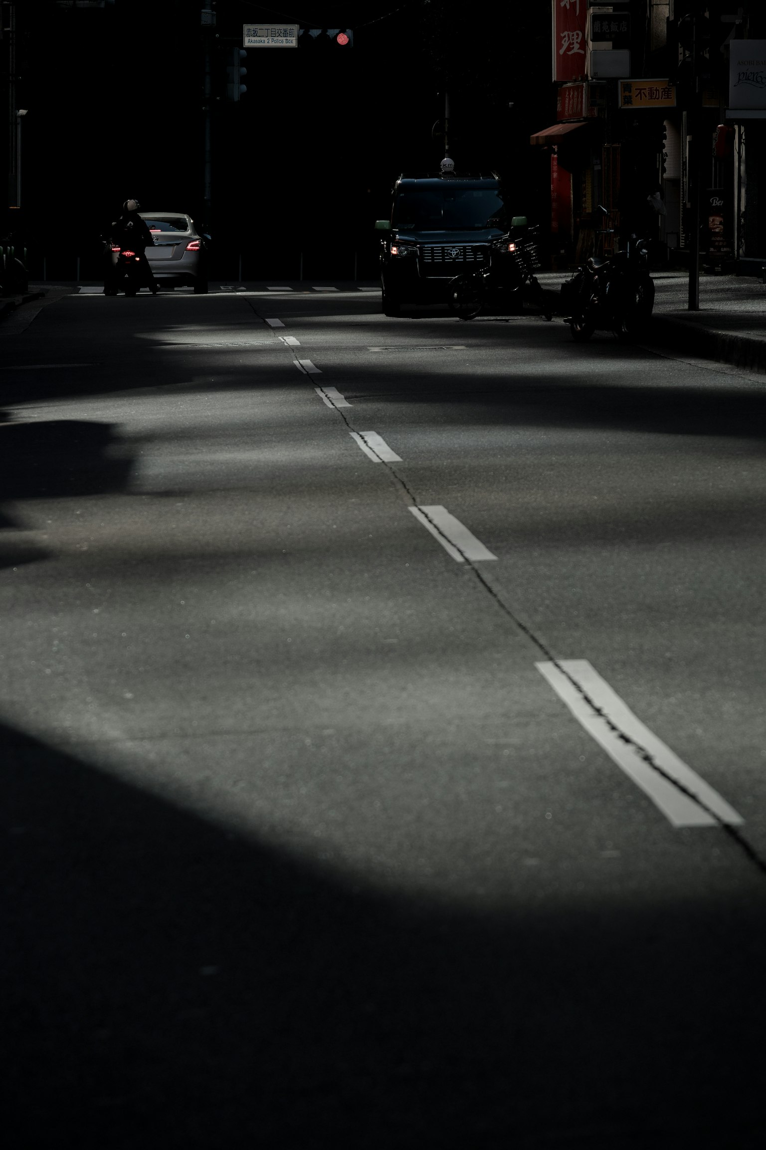 ถนนที่มีแสงน้อยพร้อมเงาและเครื่องหมายถนนสีขาว
