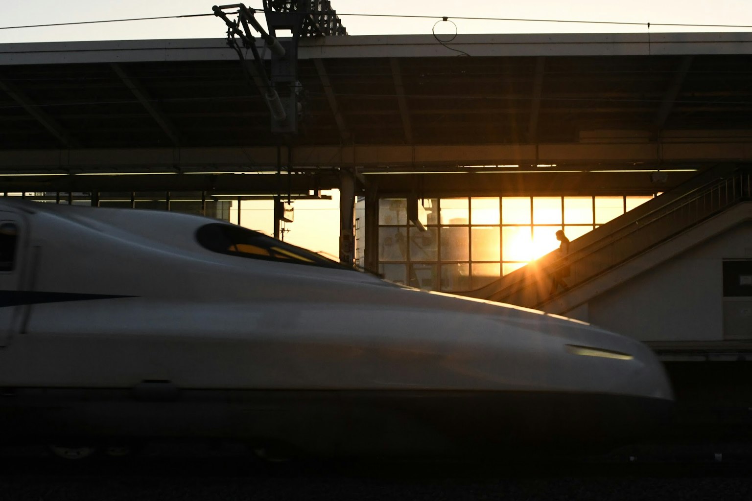 Tampilan samping Shinkansen dengan matahari terbenam di stasiun