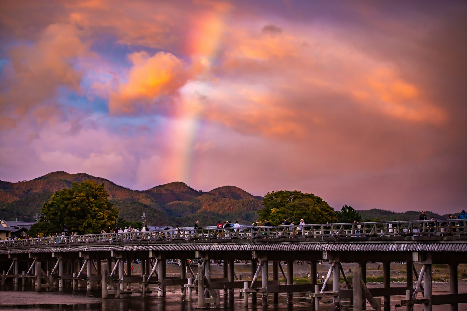 Scenic view of a bridge under a colorful sunset with a rainbow