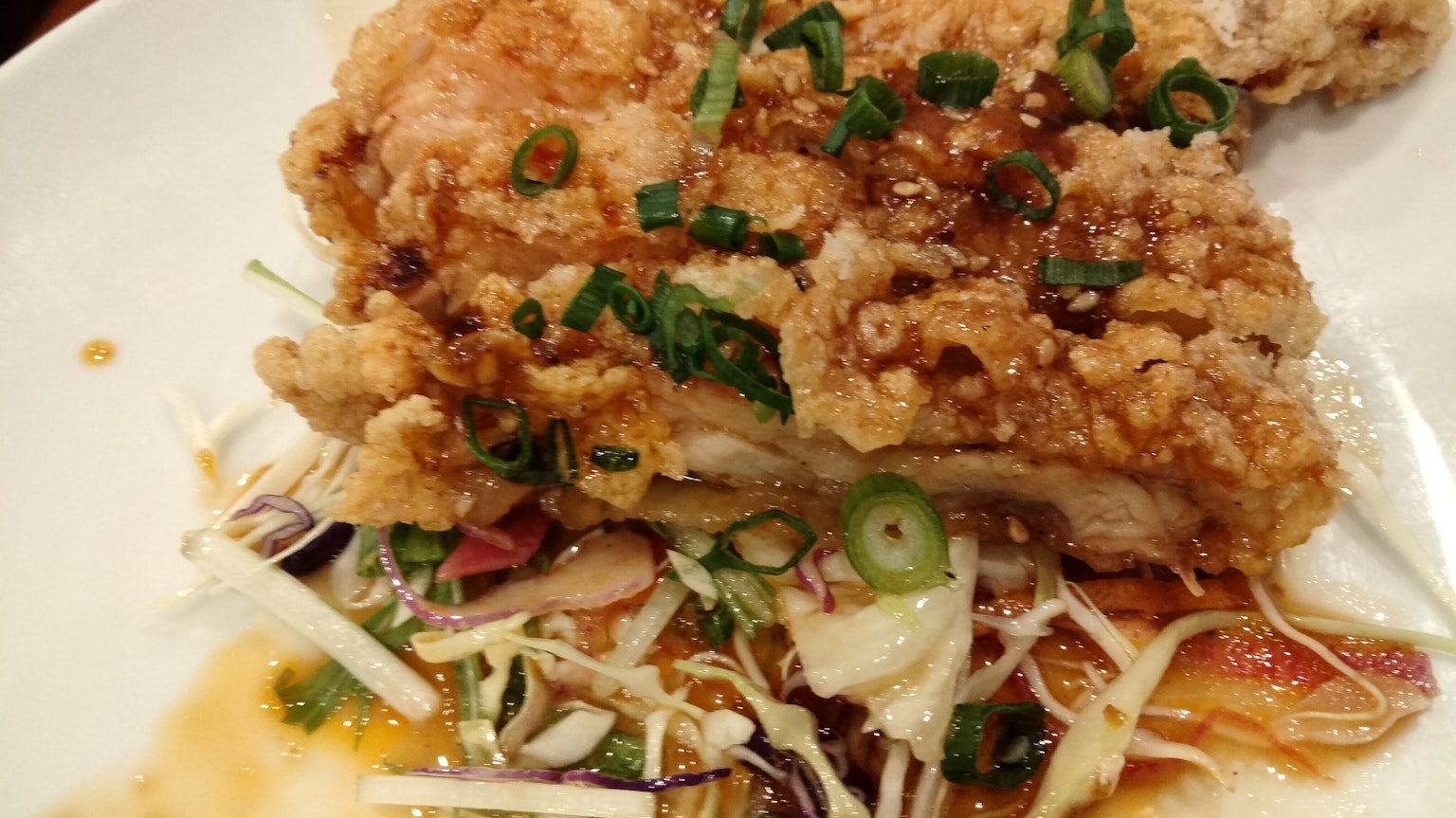 Pollo fritto guarnito con cipolle verdi servito su un letto di verdure grattugiate