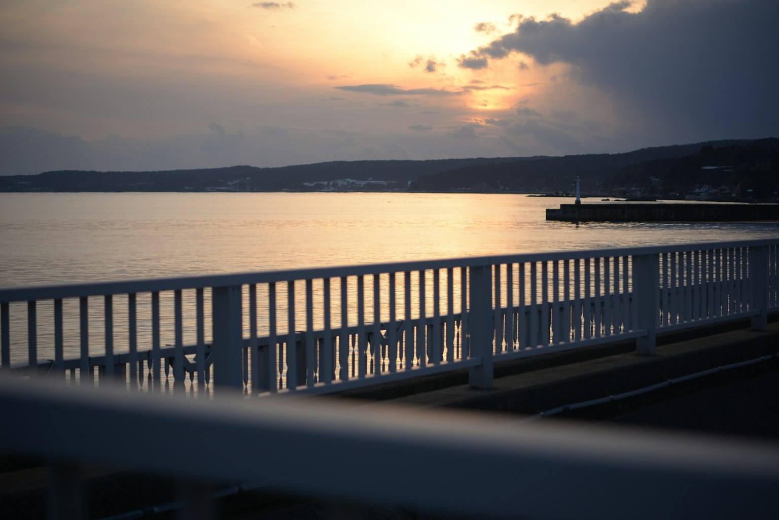 White railing along the coastline with a beautiful sunset view