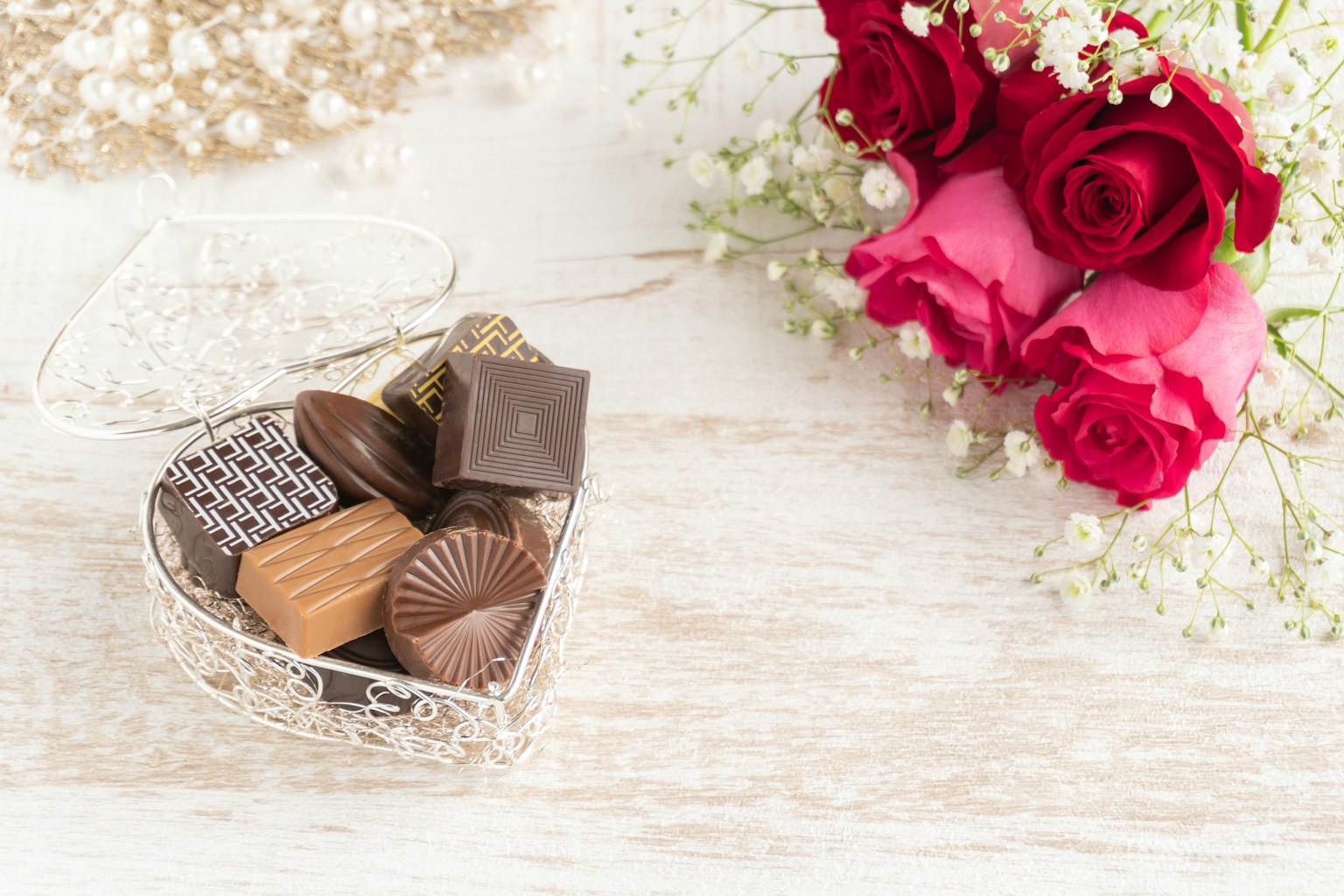 Keranjang berbentuk hati penuh cokelat dan buket mawar merah