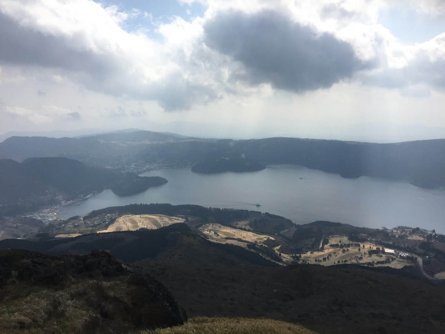 Panoramablick auf einen See umgeben von Bergen und Wolken