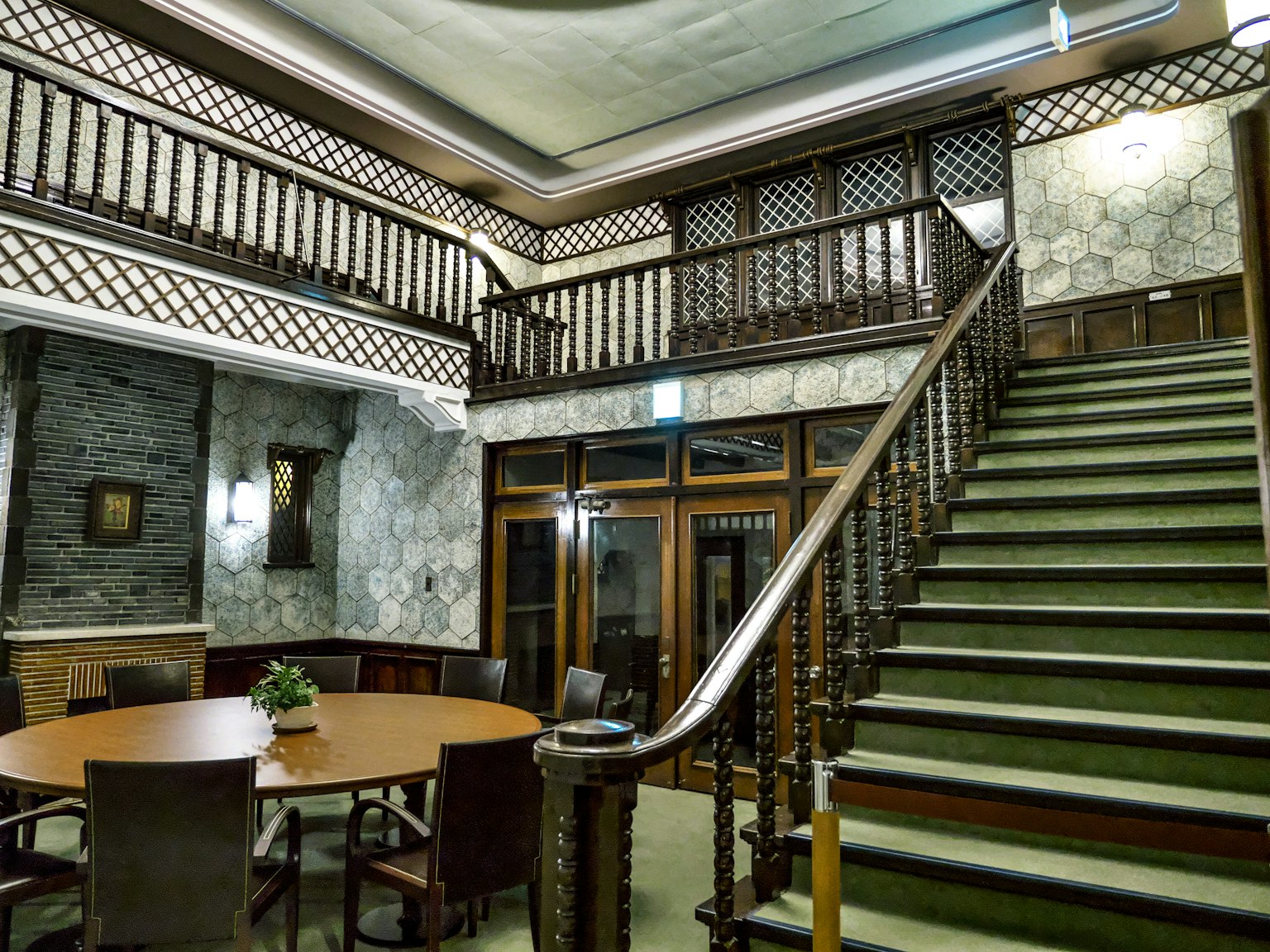 Innenaufnahme mit einer großen Treppe mit Holzgeländern und grünem Teppich