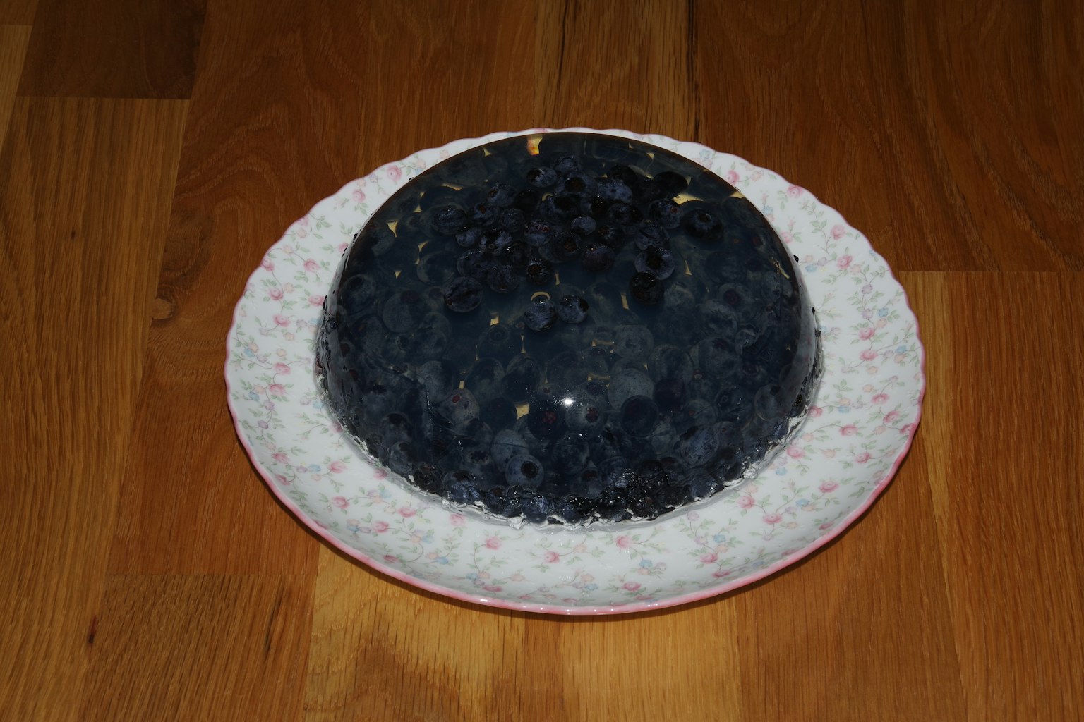 Postre de gelatina azul servido en un plato blanco con flores