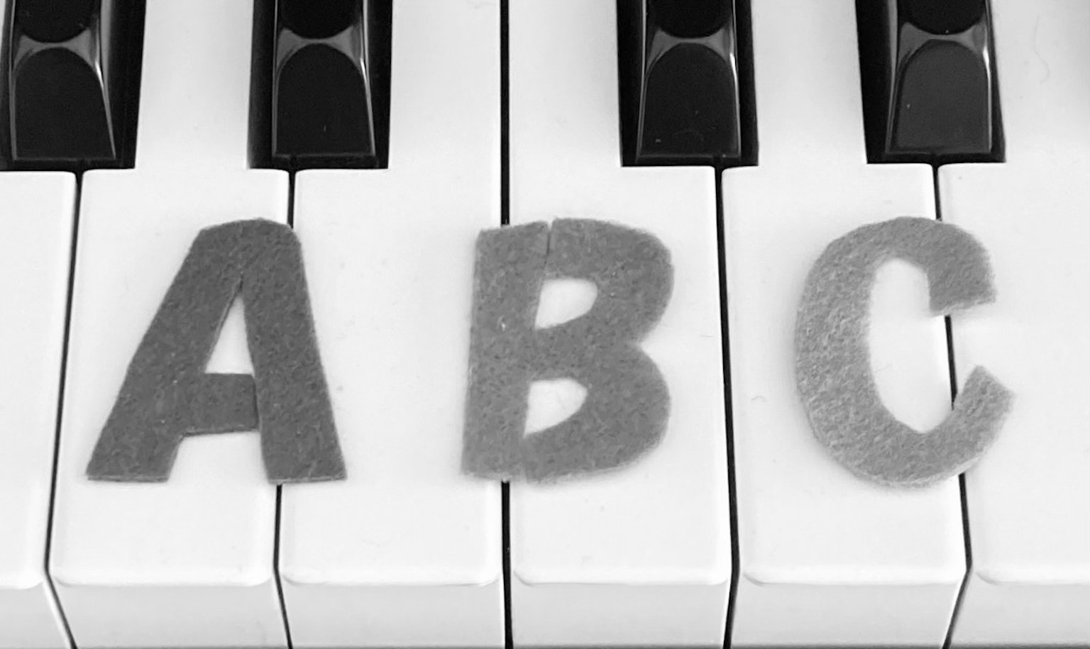 Lettere in feltro A B C posizionate su tasti di pianoforte