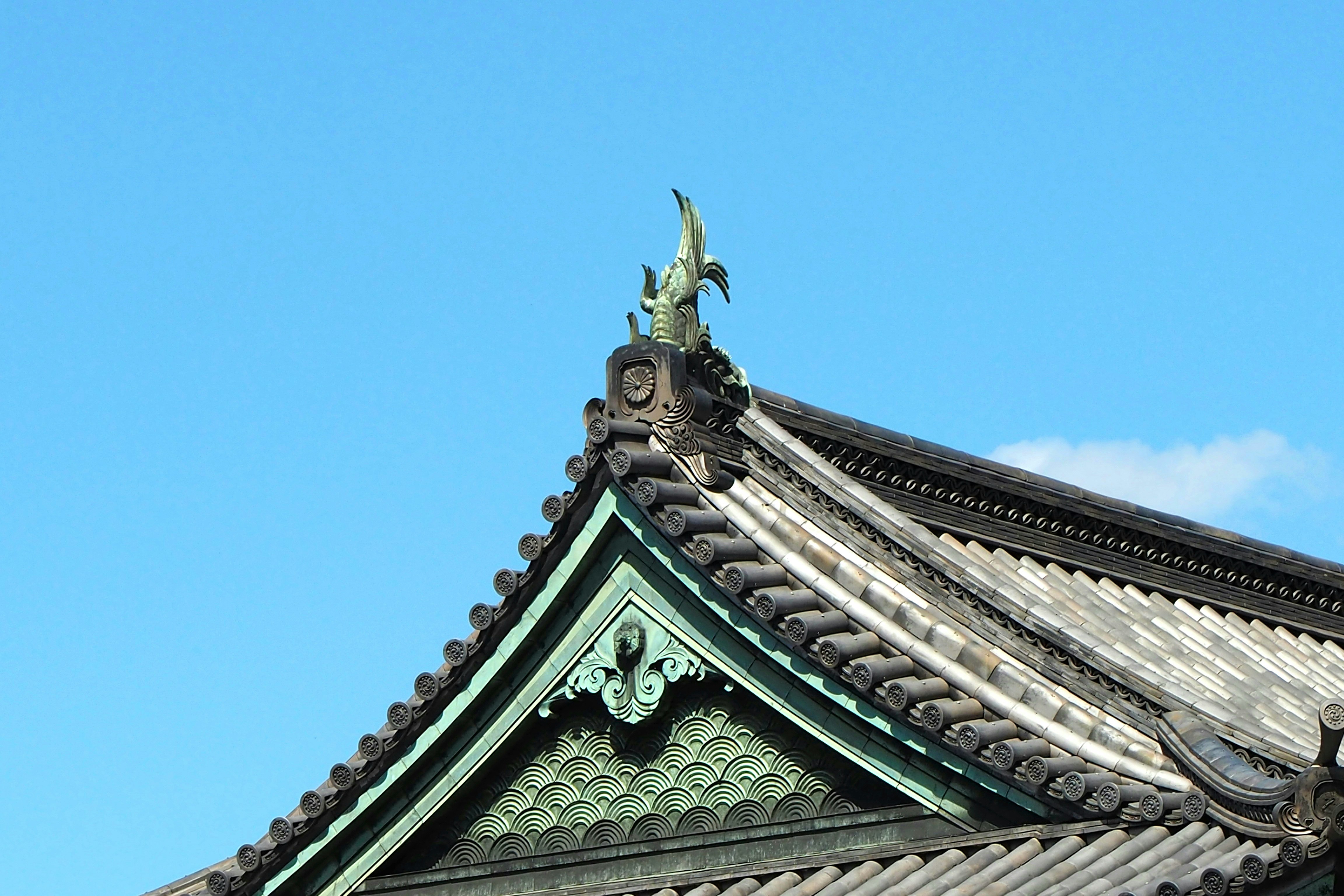 青空の下の寺院建築の屋根飾りと鬼瓦