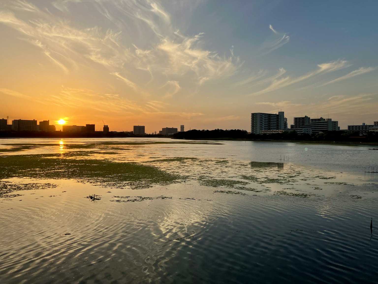 Vista panoramica di un lago al tramonto con riflessi e skyline della città